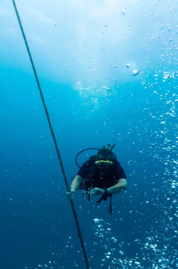Scuba diver checking his dive computer to ascend safely, during the Advanced Open Water Scuba Diving Certification.