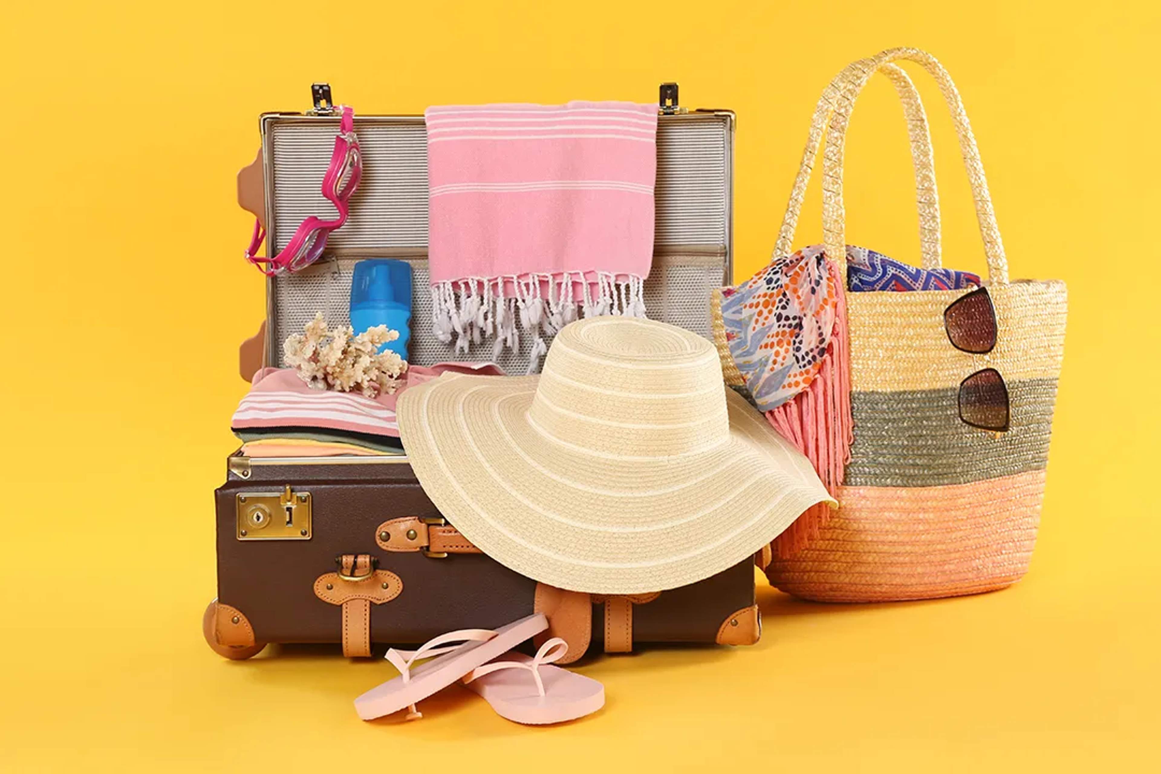 Maleta abierta con ropa de playa, sombrero, sandalias, toalla y accesorios listos para viaje a Vallarta