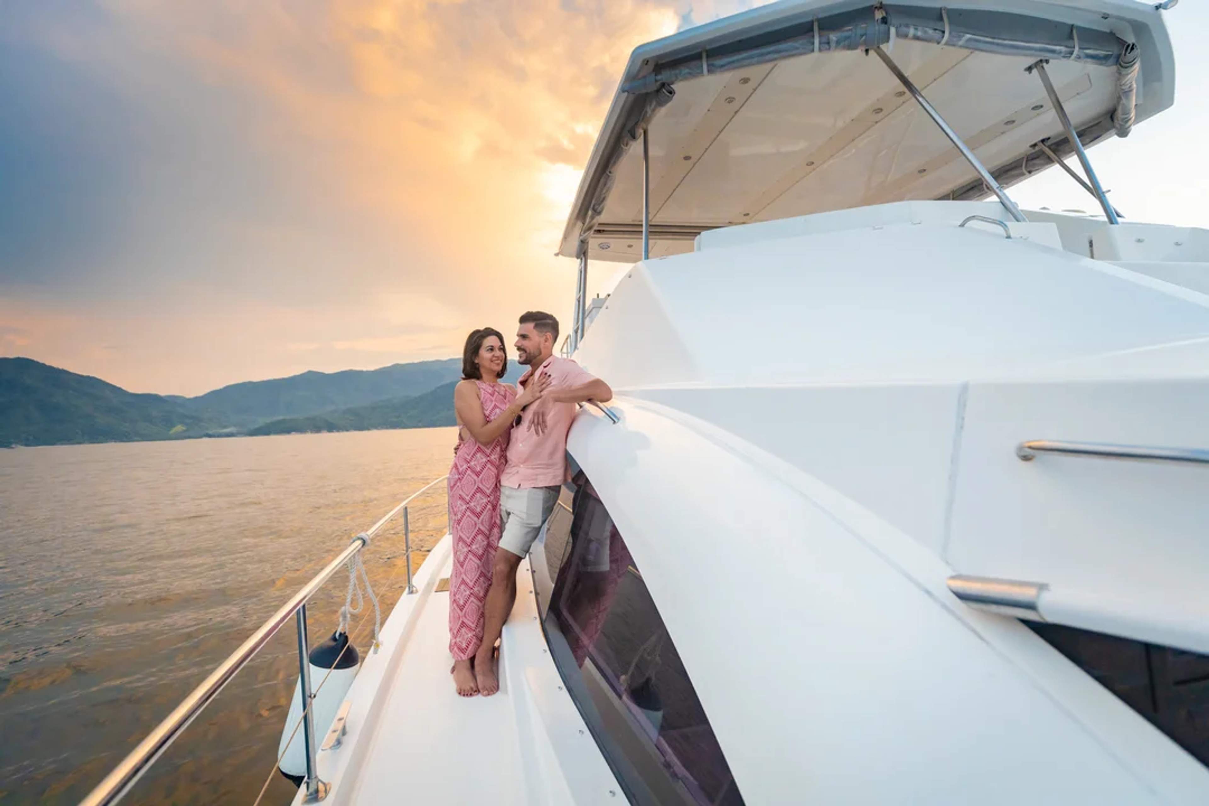 Pareja disfruta un romántico atardecer a bordo de un yate en la bahía de Puerto Vallarta.
