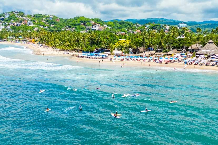 Vista aérea de la playa de Sayulita cerca de Punta Mita, con surf, mar turquesa y costa tropical.