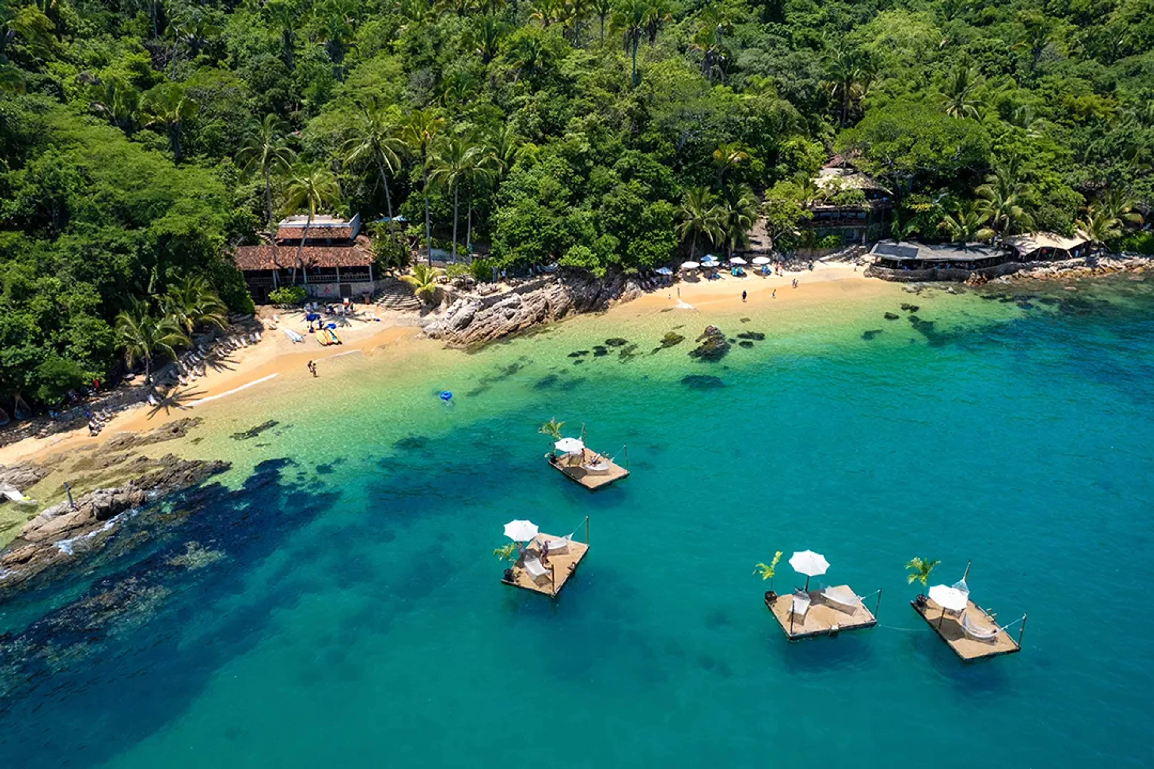 Las Caletas beach in Puerto Vallarta with floating platforms, turquoise water and lush jungle coastline