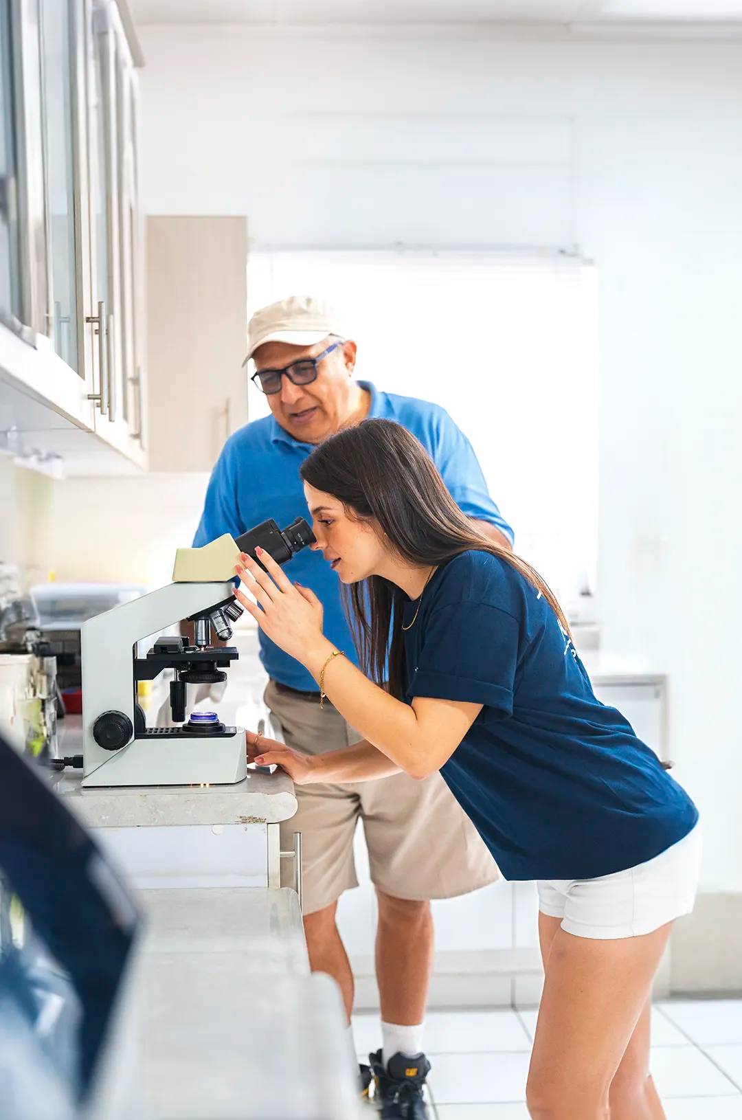 Girl looking at some samples through a microscope on a veterinarian lab.