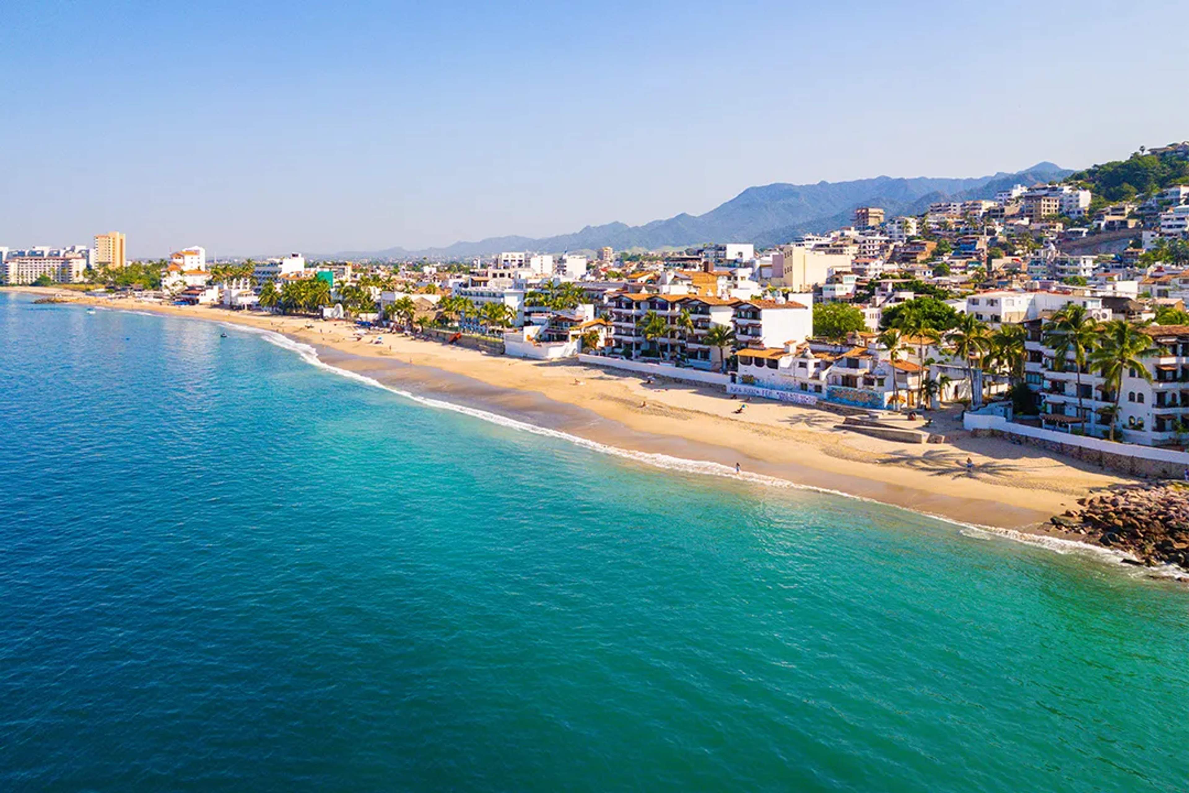 Aerial view of Playa Camarones in Puerto Vallarta with golden sand, turquoise water and city skyline
