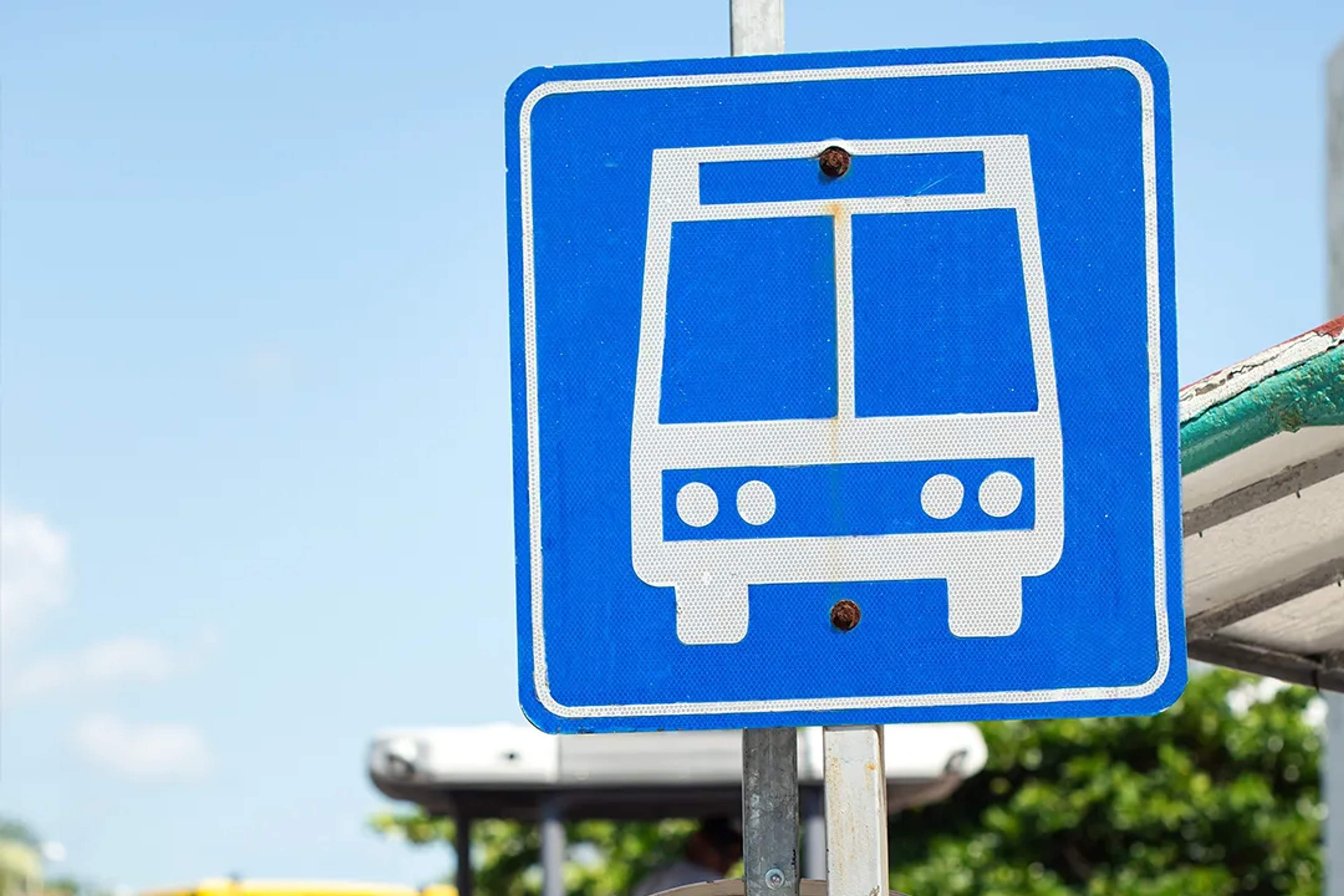 Señal azul de parada de autobús bajo un cielo soleado, indica transporte público.