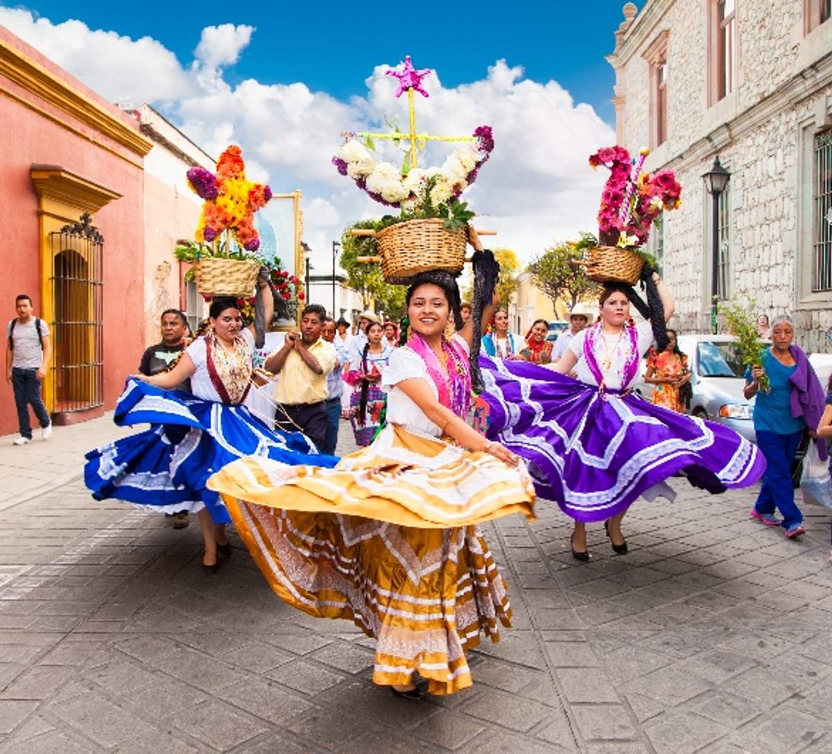 Women in colorful traditional dresses dance with flower baskets on their heads during the pilgrimage of the Virgin of the Rosary in Talpa, Mexico.