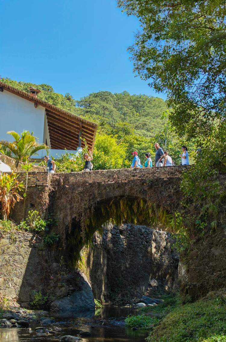 Travelers crossing an old stone bridge in San Sebastian del Oeste.
