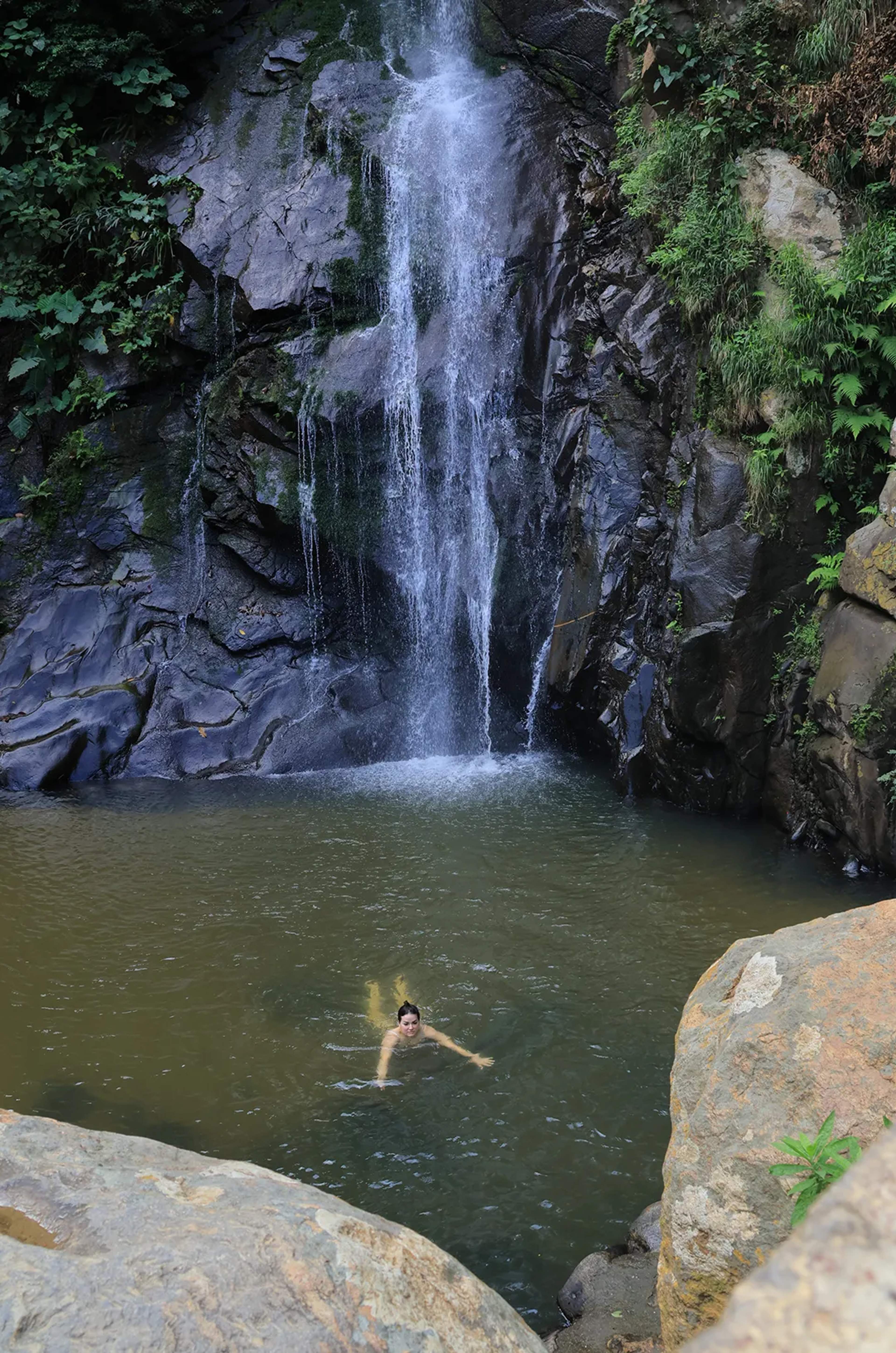 Guest swimming beneath Yelapa hidden waterfall on jungle hike tour near Puerto Vallarta, natural pool oasis