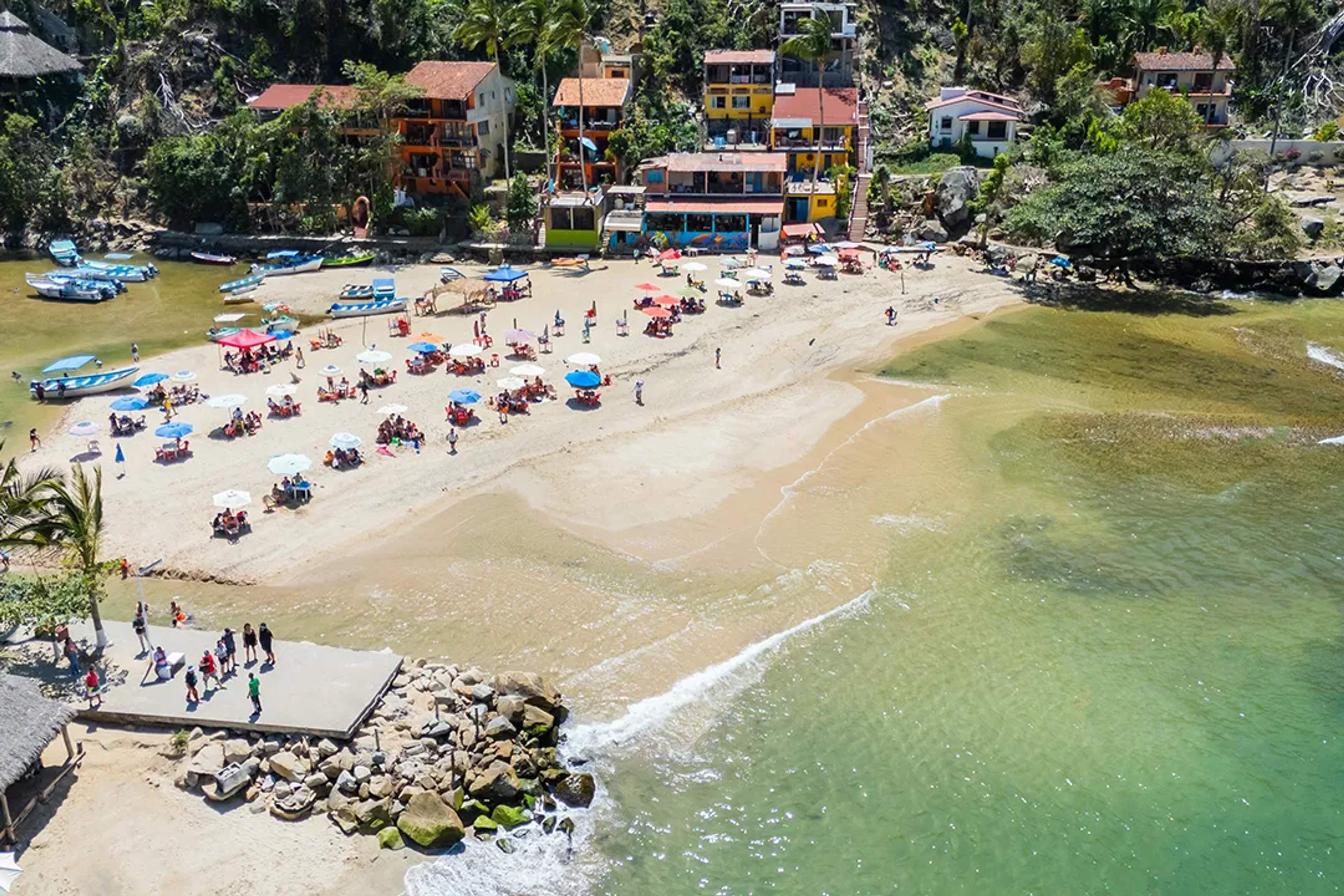 Sombrillas y mesas decoran la playa de Boca de Tomatlán, donde locales y visitantes descansan.