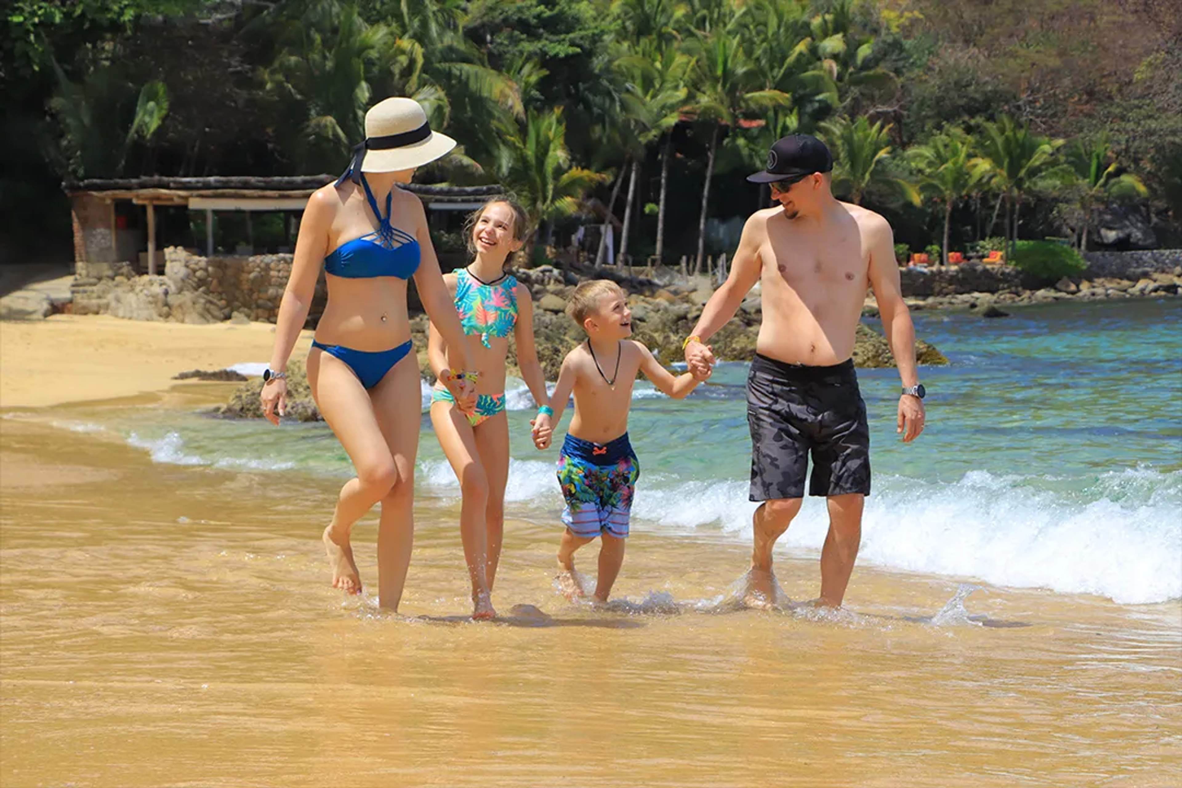 Familia disfruta un día de playa en Las Caletas, caminando por la orilla con entorno tropical