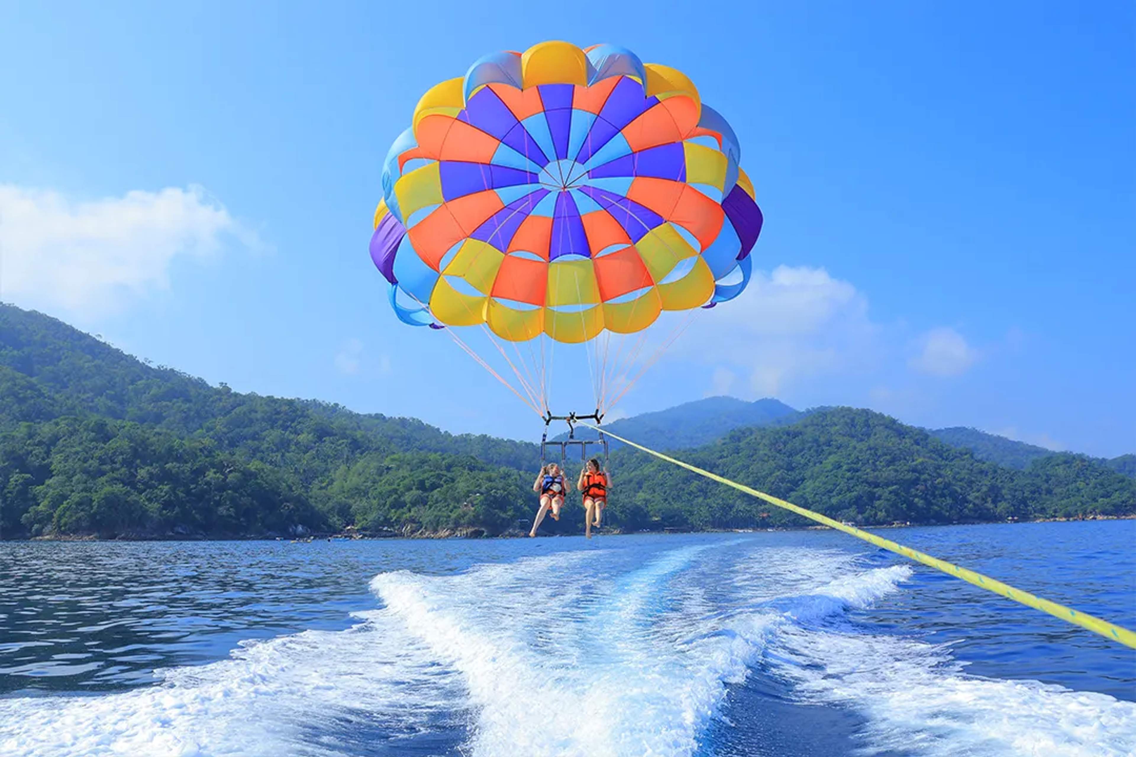 Colorful parasailing over the ocean in Puerto Vallarta with two guests enjoying the Ocean Mania tour