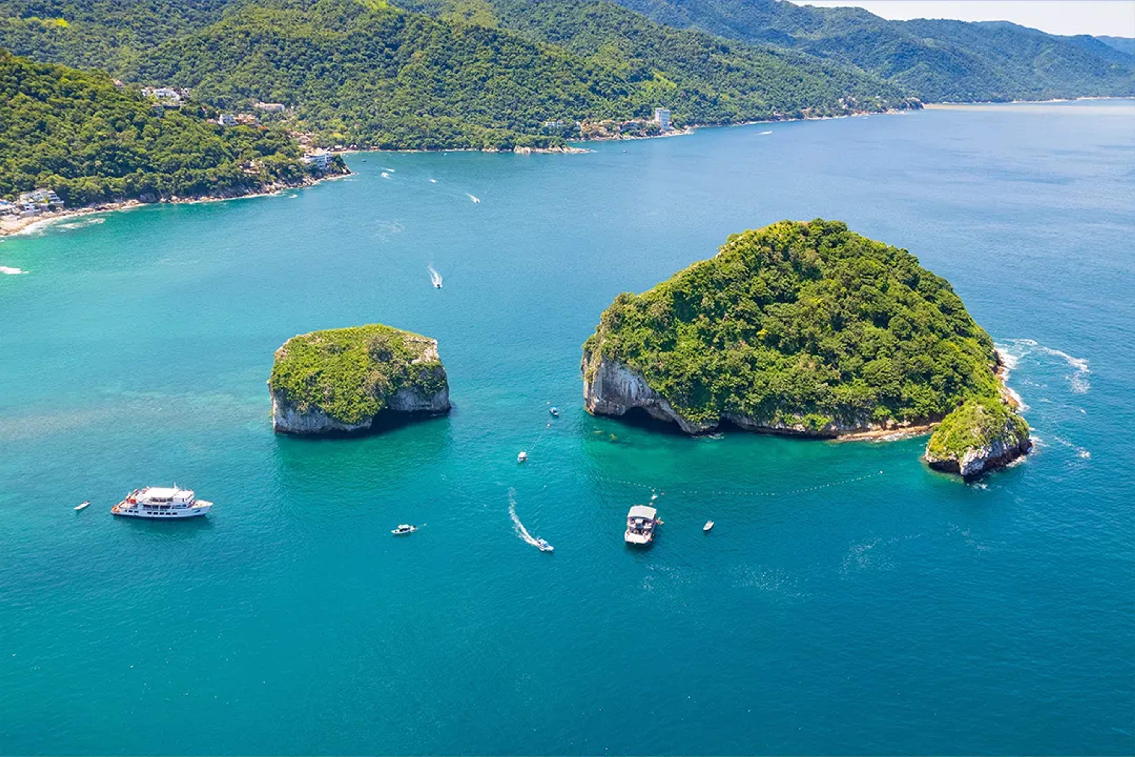 Aerial view of Los Arcos in Puerto Vallarta, featuring small islands and a boat in the turquoise waters.