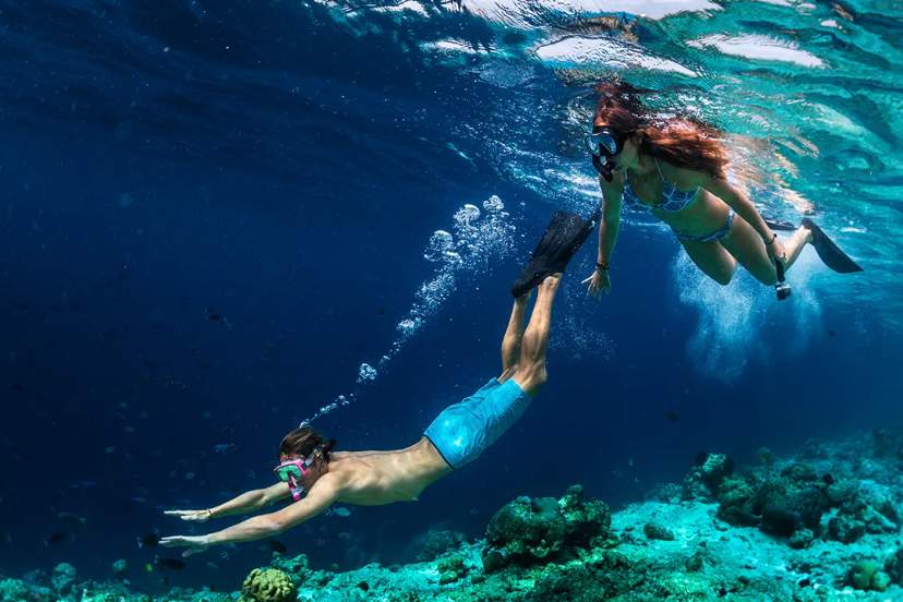 Couple snorkeling together over vibrant coral reefs, exploring marine life in crystal-clear tropical waters in Mexico
