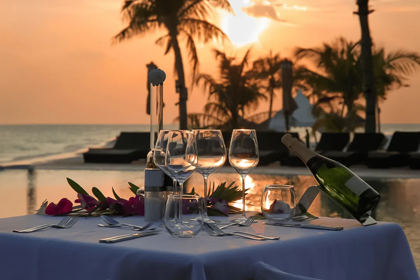 Mesa para cena romántica en Puerto Vallarta, con vino y vista al atardecer sobre el mar.