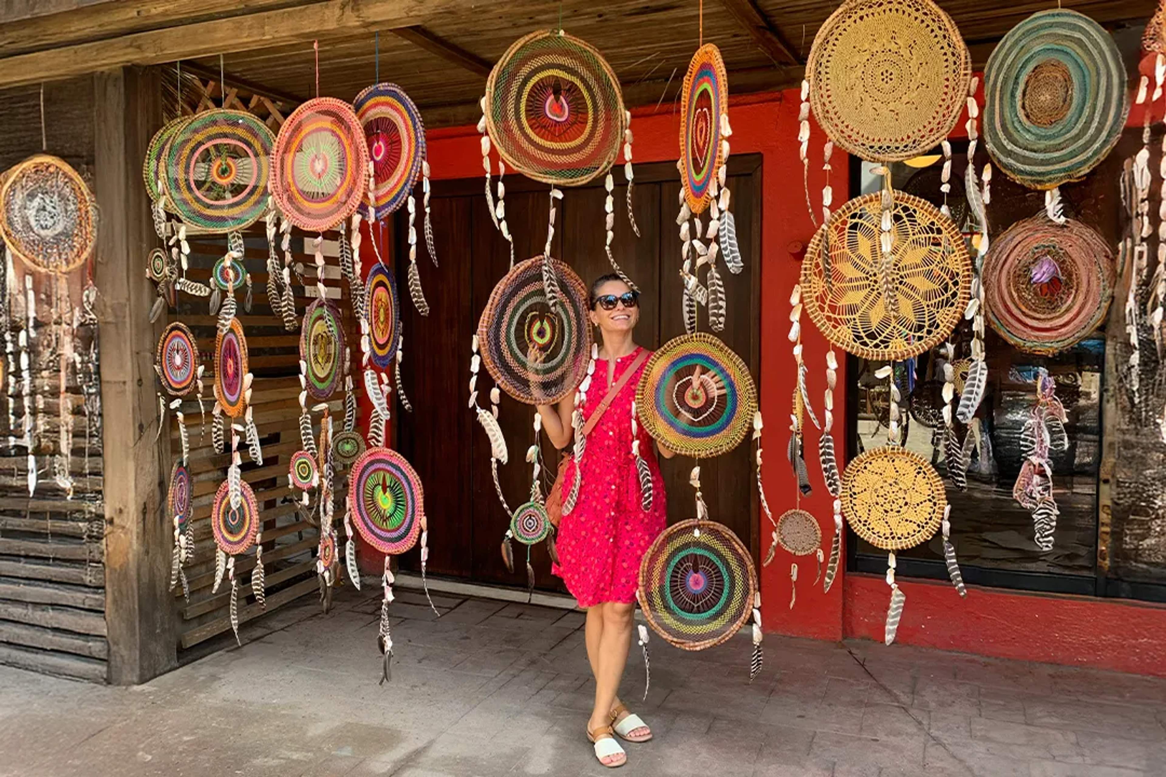 Woman in red dress surrounded by colorful dreamcatchers at a market in Sayulita.