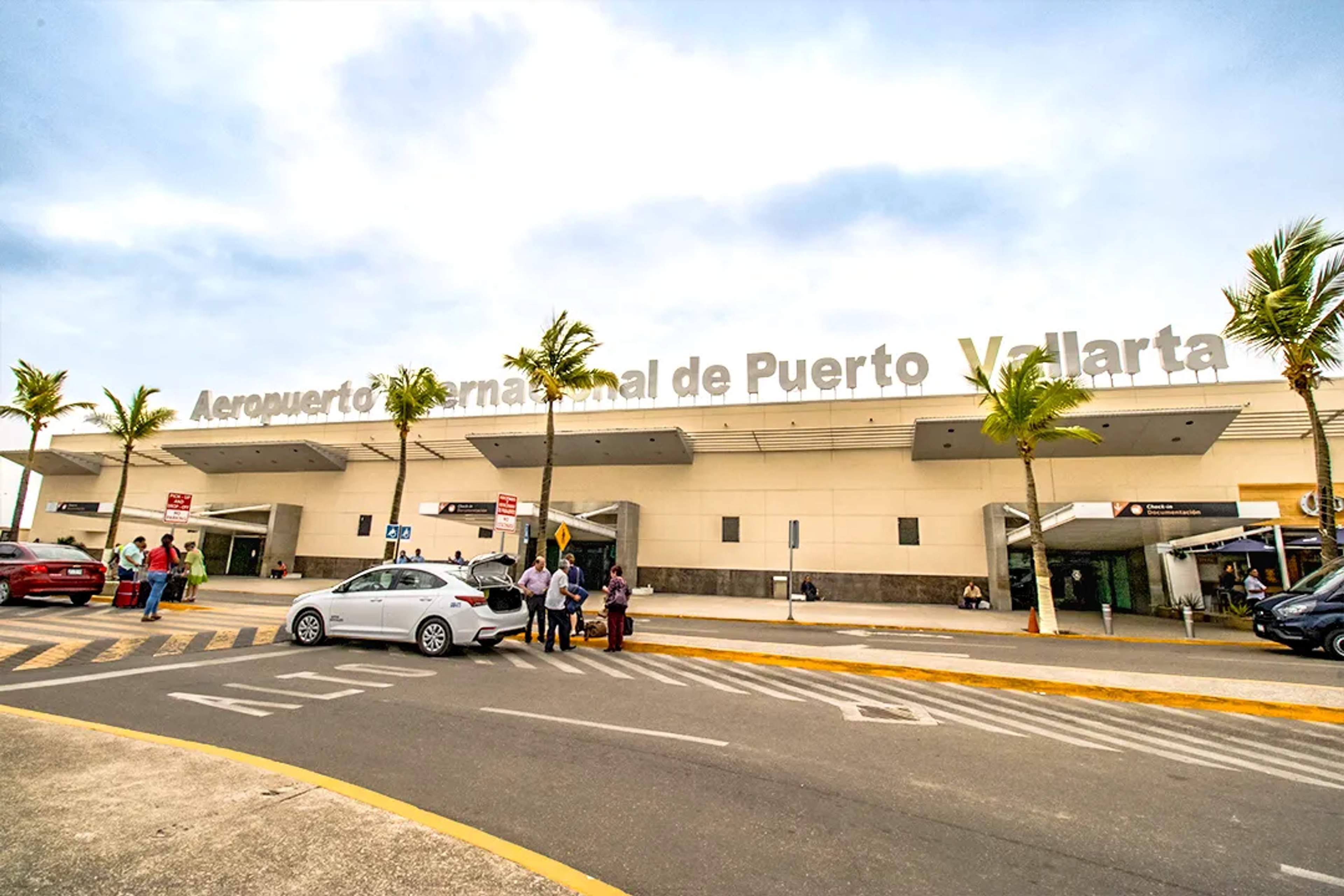 Travelers arrive at Puerto Vallarta Airport under sunny skies and palm trees.
