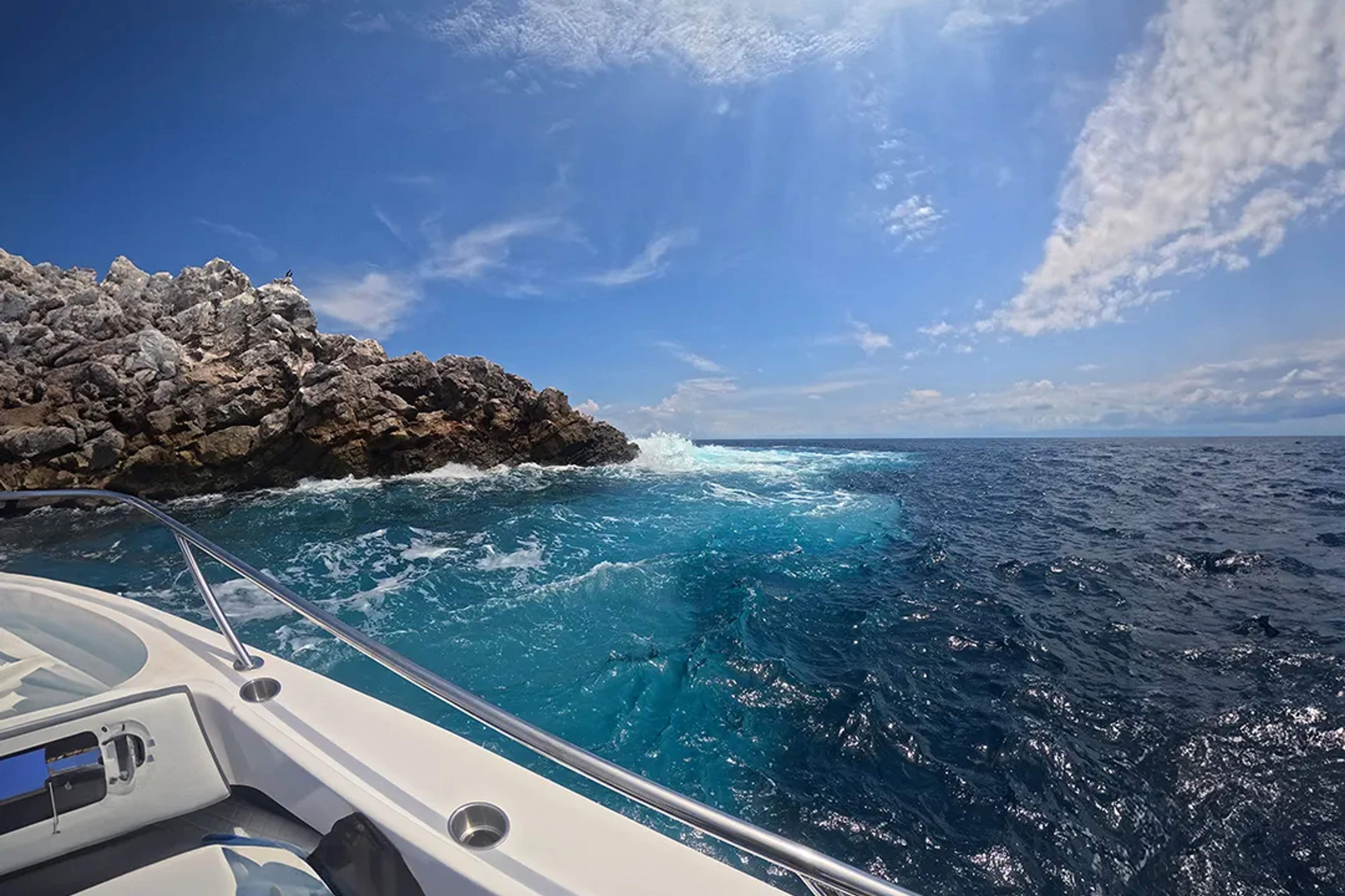 Boat approaches rocky islet of La Corbetaña, where turquoise waters meet the deep blue Pacific.