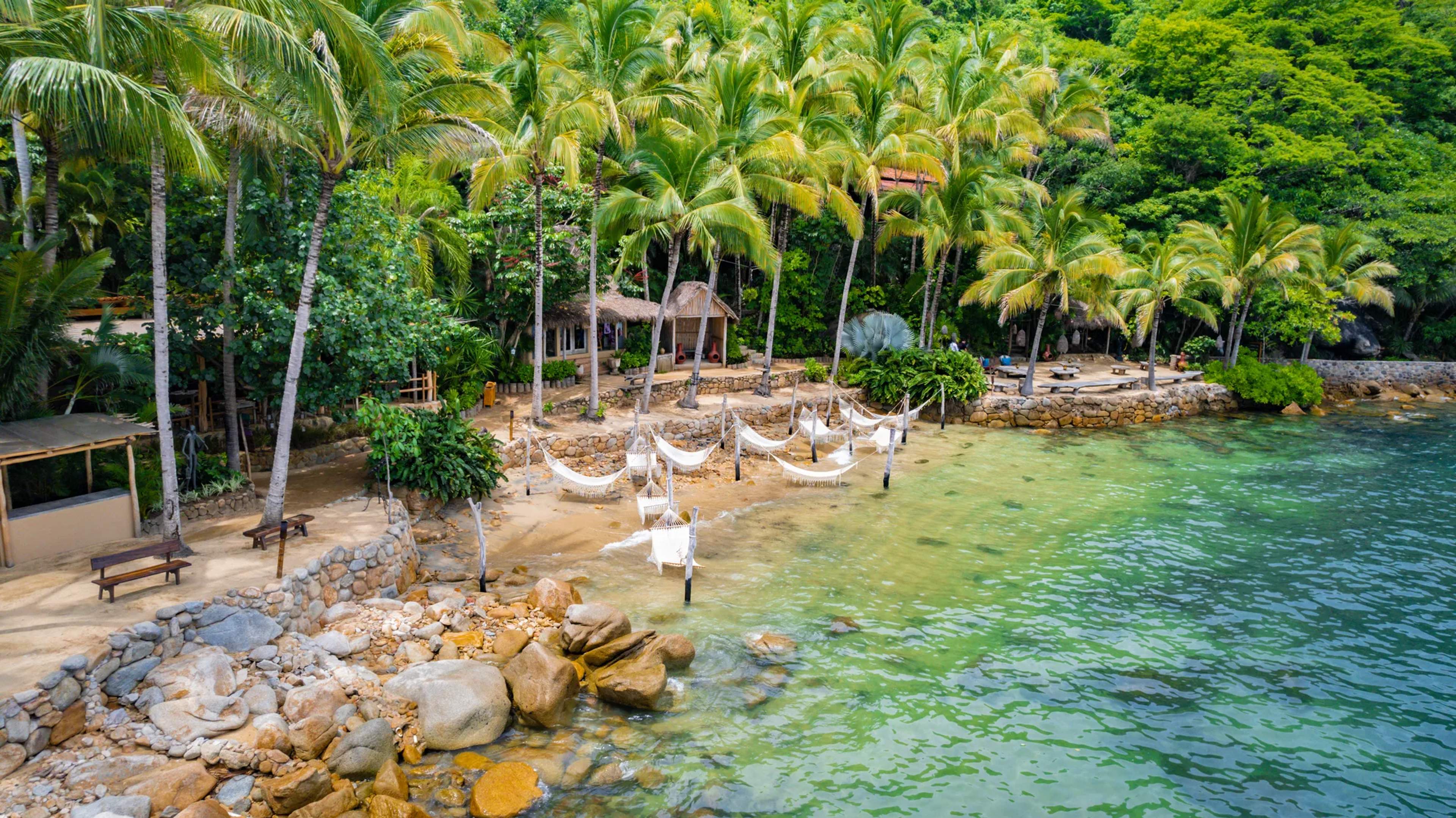 Playa escondida de Las Caletas con hamacas entre palmeras, agua turquesa y estructuras rústicas de madera en la selva.