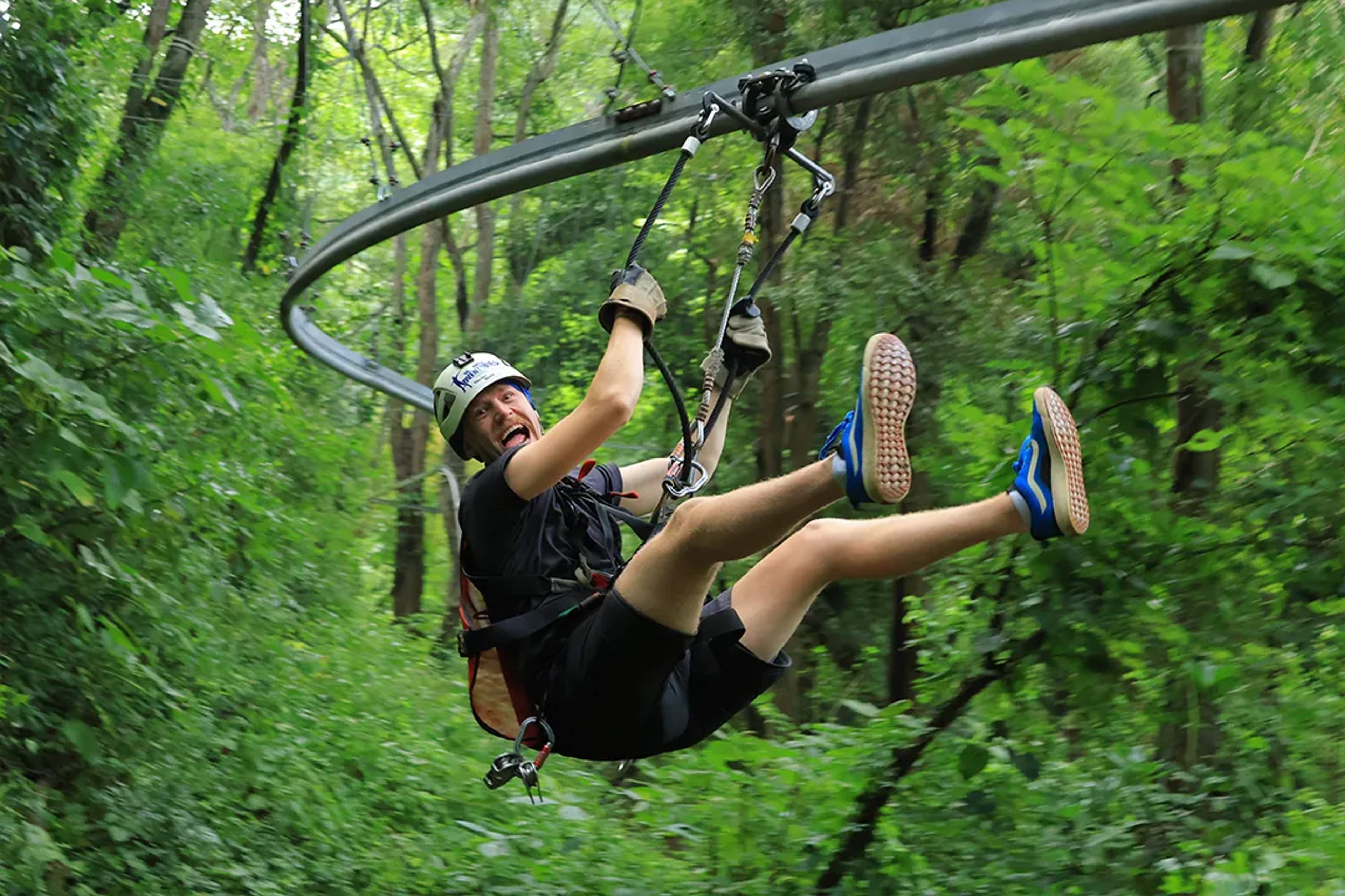 Adventurer twists with excitement on a jungle roller coaster zipline, laughing through the ride at Extreme Adventure.