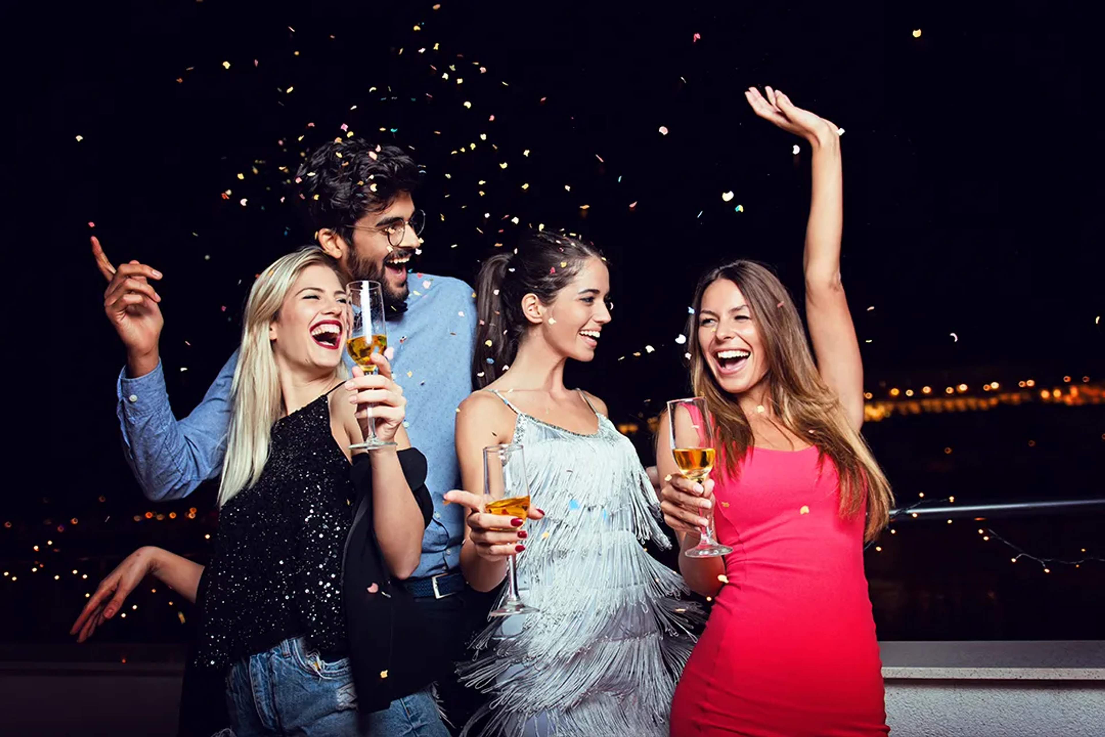 Friends celebrating New Year’s Eve with drinks and confetti during a festive night out in Puerto Vallarta