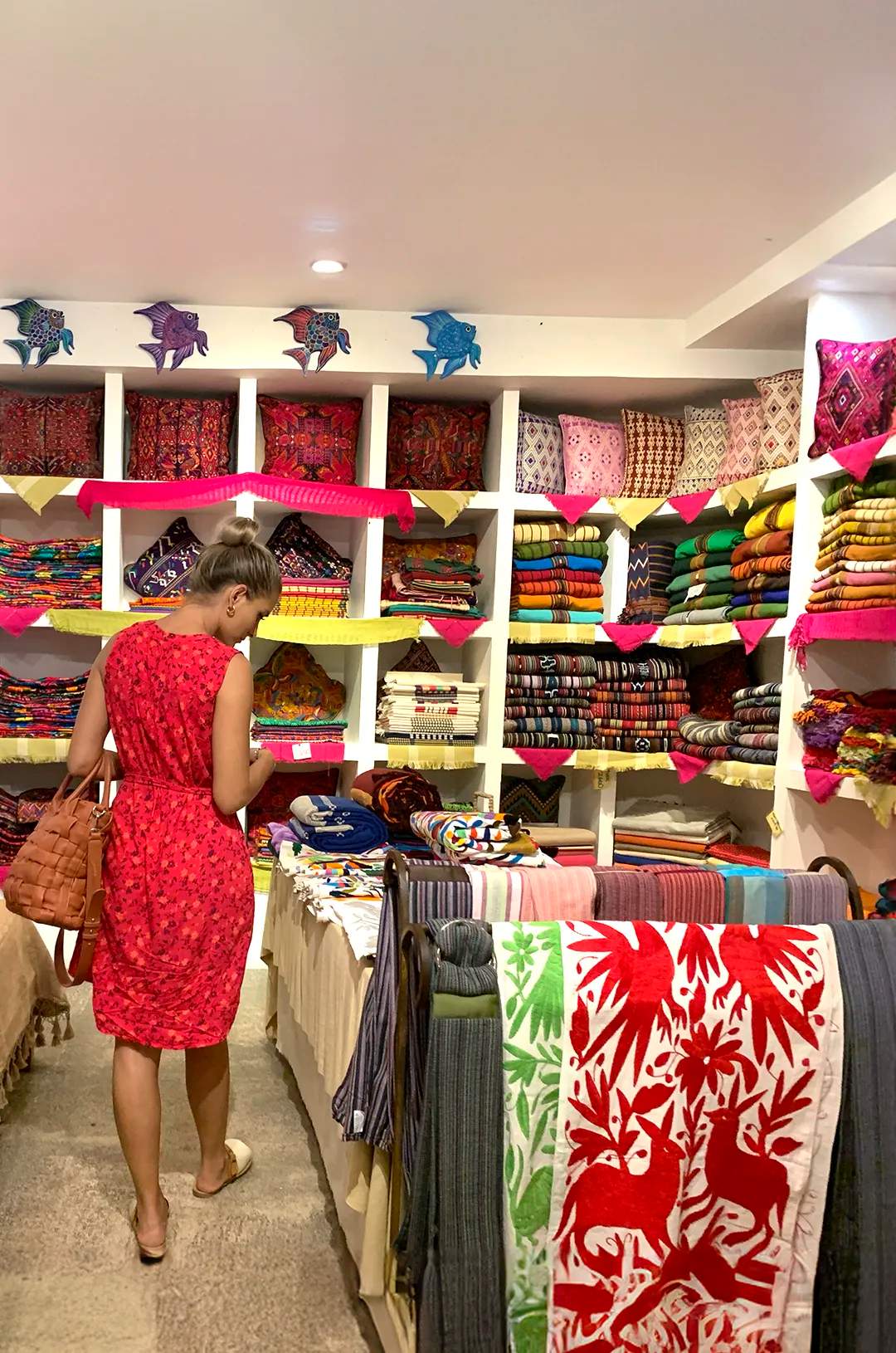 Woman browsing traditional textiles in a vibrant shop in Sayulita, Mexico, during a Sayulita shopping tour.