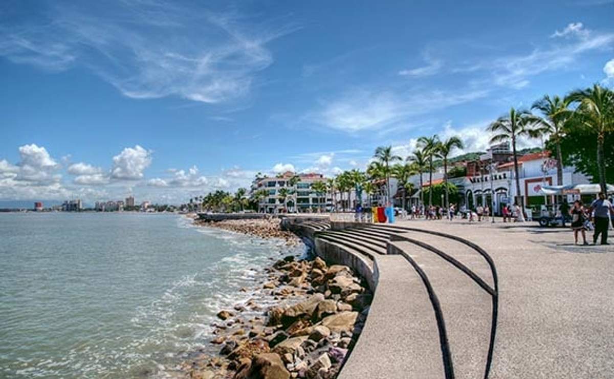Personas caminando por el Malecón, el paseo marítimo de Puerto Vallarta, con tiendas, restaurantes y vistas panorámicas al océano.