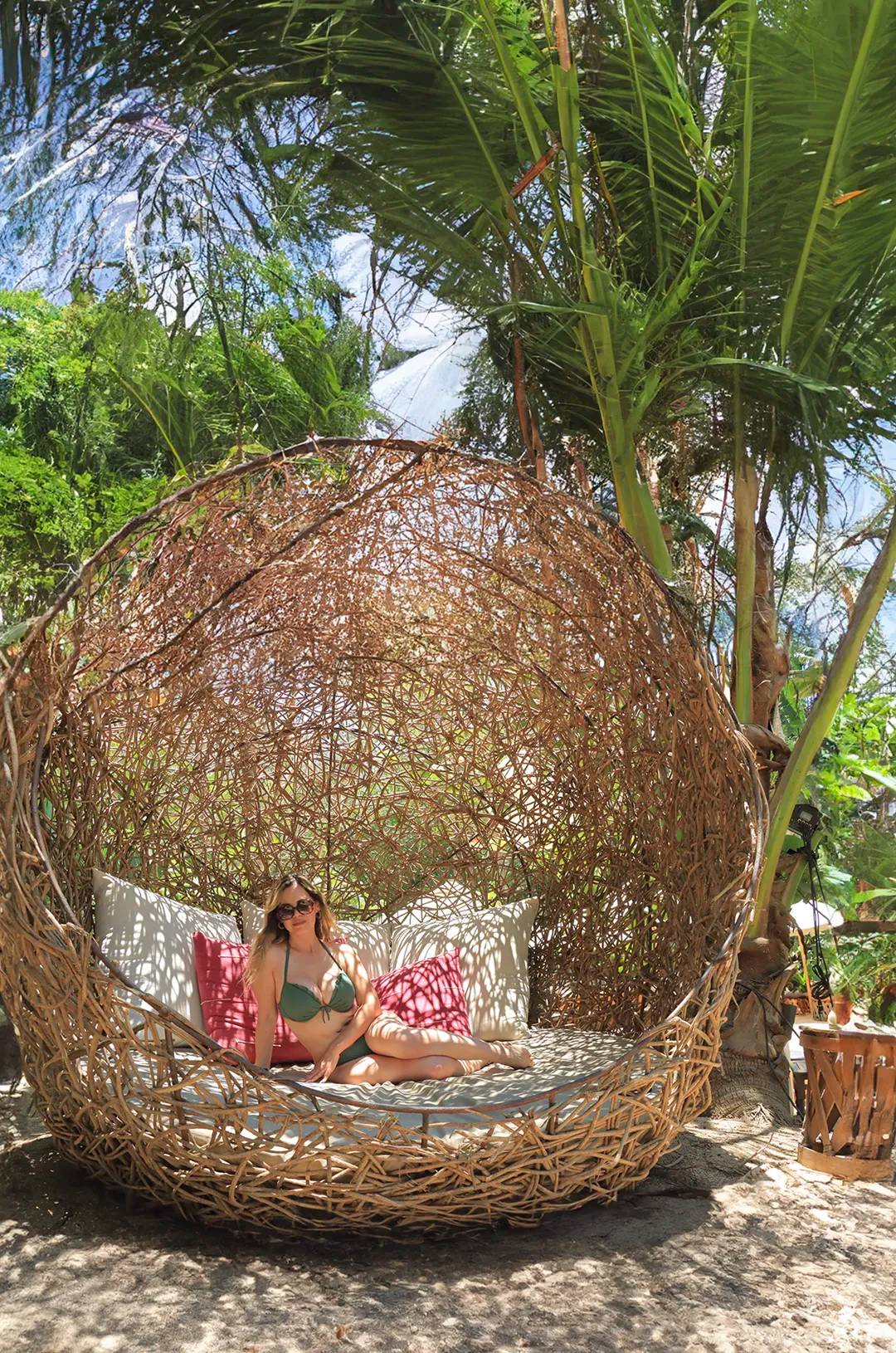 Mujer relajándose en una silla colgante boho-chic en la exclusiva playa Majahuitas, rodeada de exuberante vegetación tropical