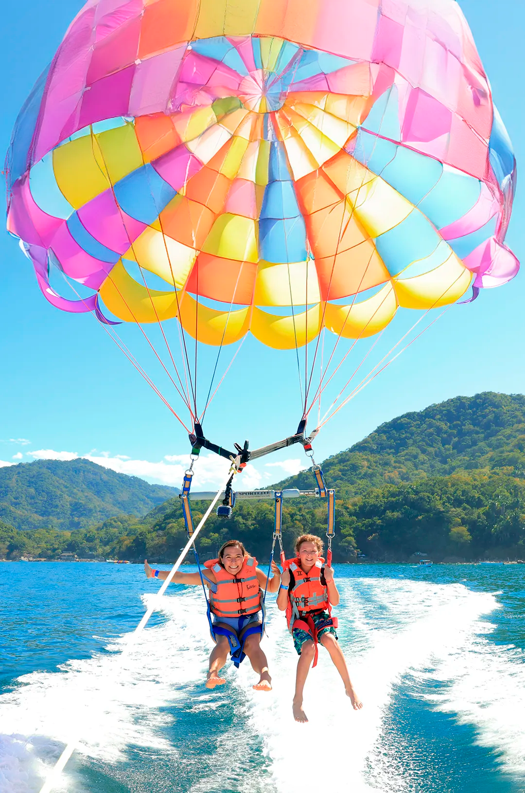 Mom and daughter parasailing over the sea at Las Caletas beach, one of the most fun Puerto Vallarta family activities.