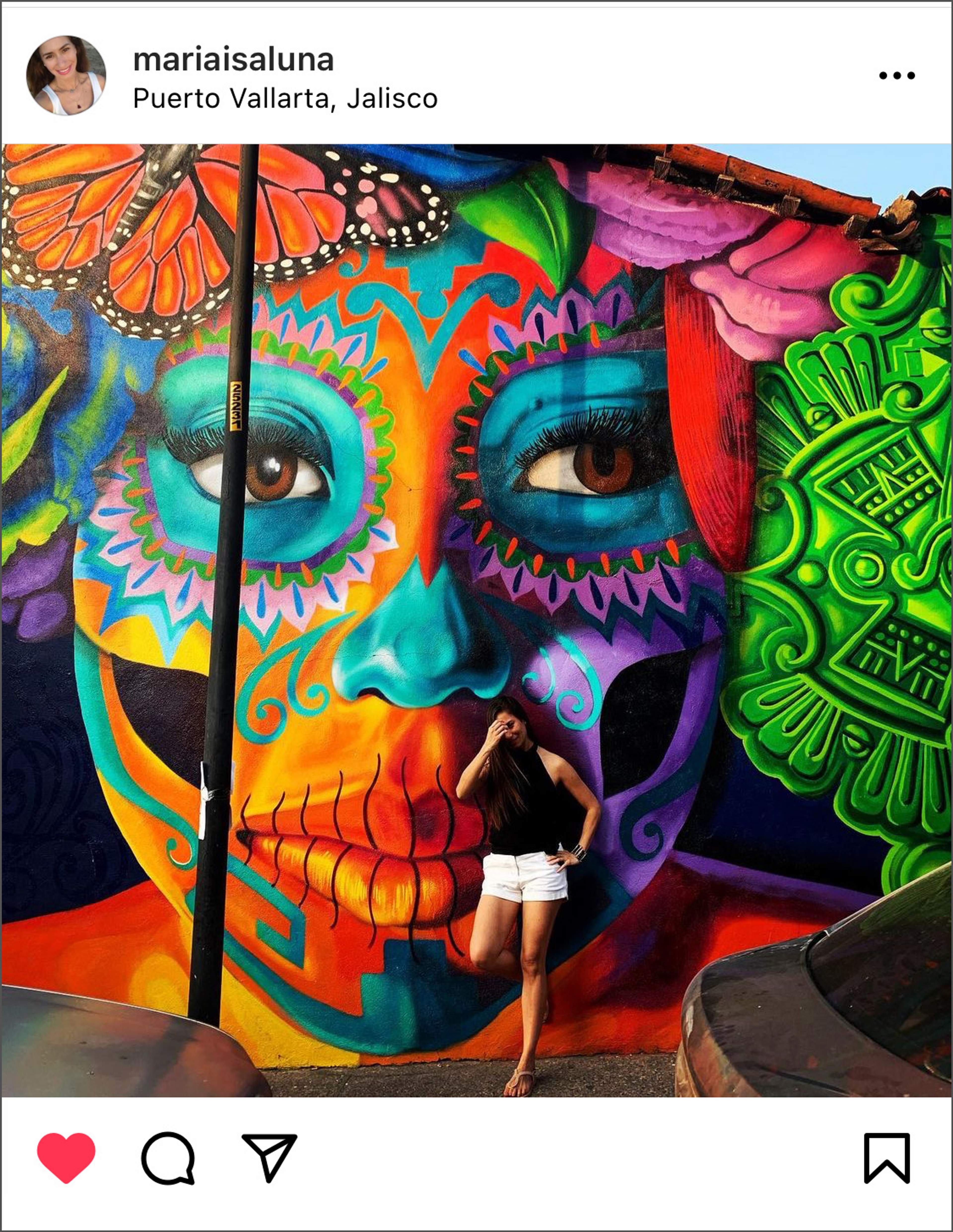 Mujer posando frente a un colorido mural del Día de los Muertos en Puerto Vallarta, Jalisco.
