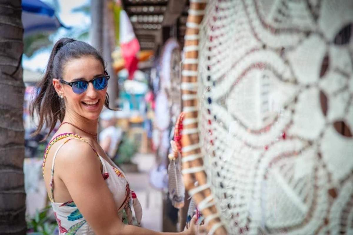 A smiling woman shops for handmade crafts during Christmas festivities in Mexico, reflecting the vibrant holiday spirit.