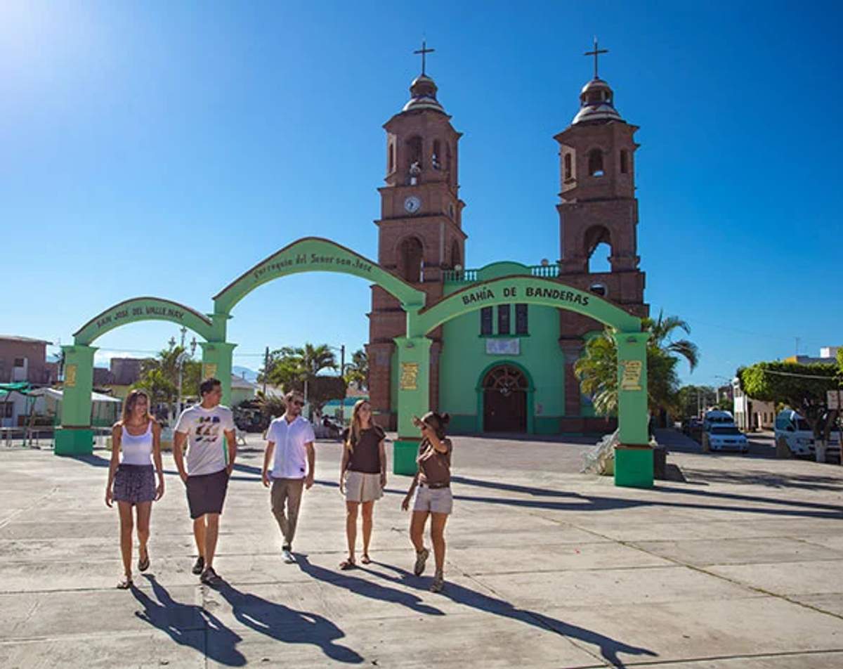 Grupo caminando frente al arco y la iglesia de Bahía de Banderas en Puerto Vallarta.