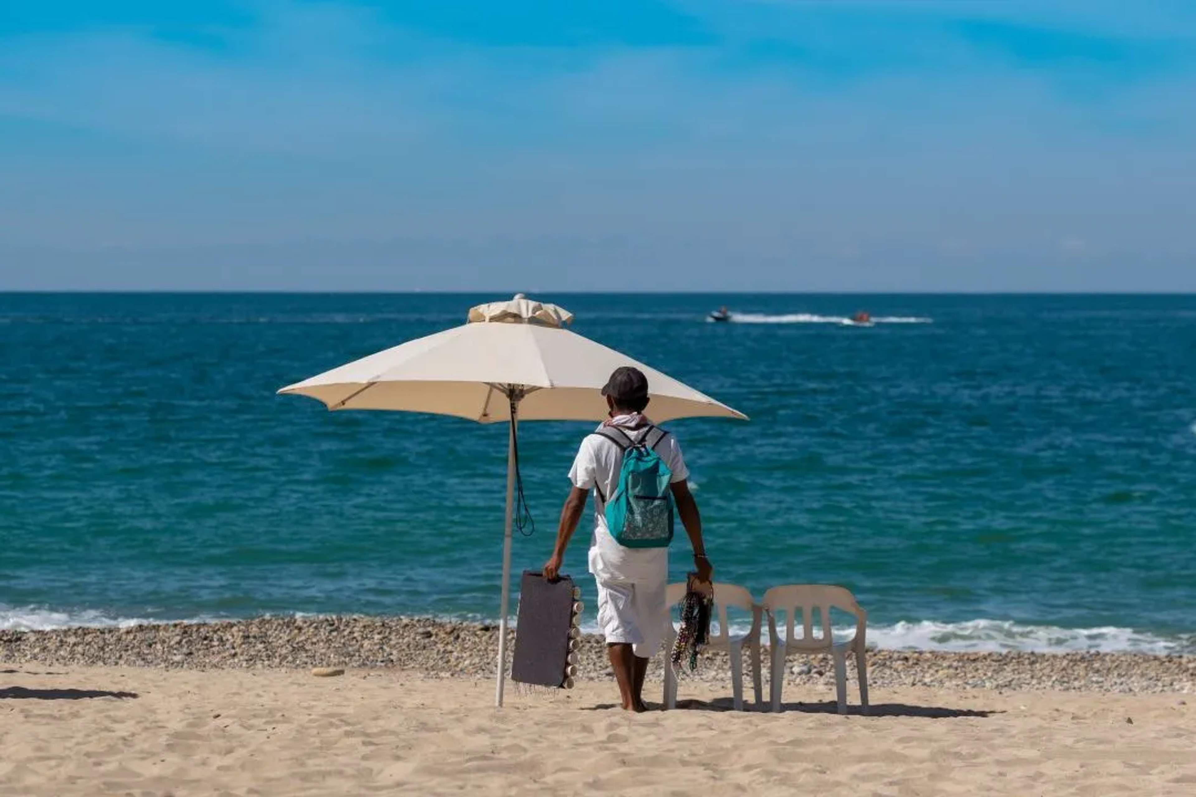 A man walking towards chairs on a beach in Puerto Vallarta