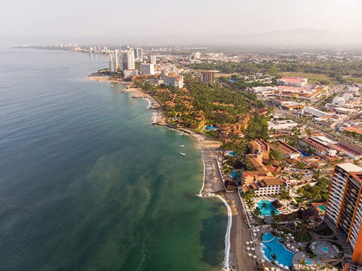 Aerial view of Puerto Vallarta's Hotel Zone featuring hotels, resorts, and beaches along the coastline with the city in the background.