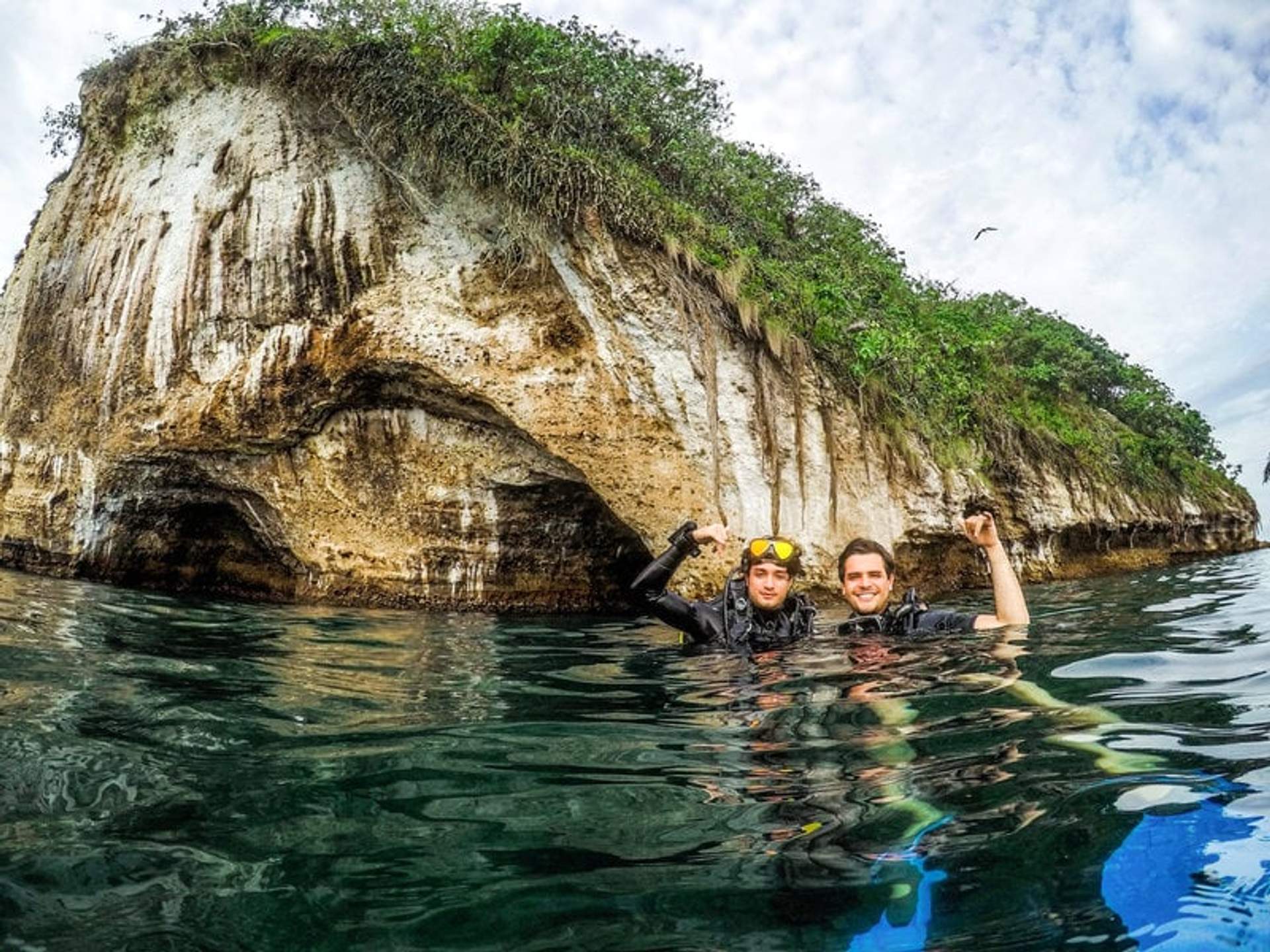 Two divers enjoying the waters near Los Arcos in Puerto Vallarta, with rocky cliffs in the background.