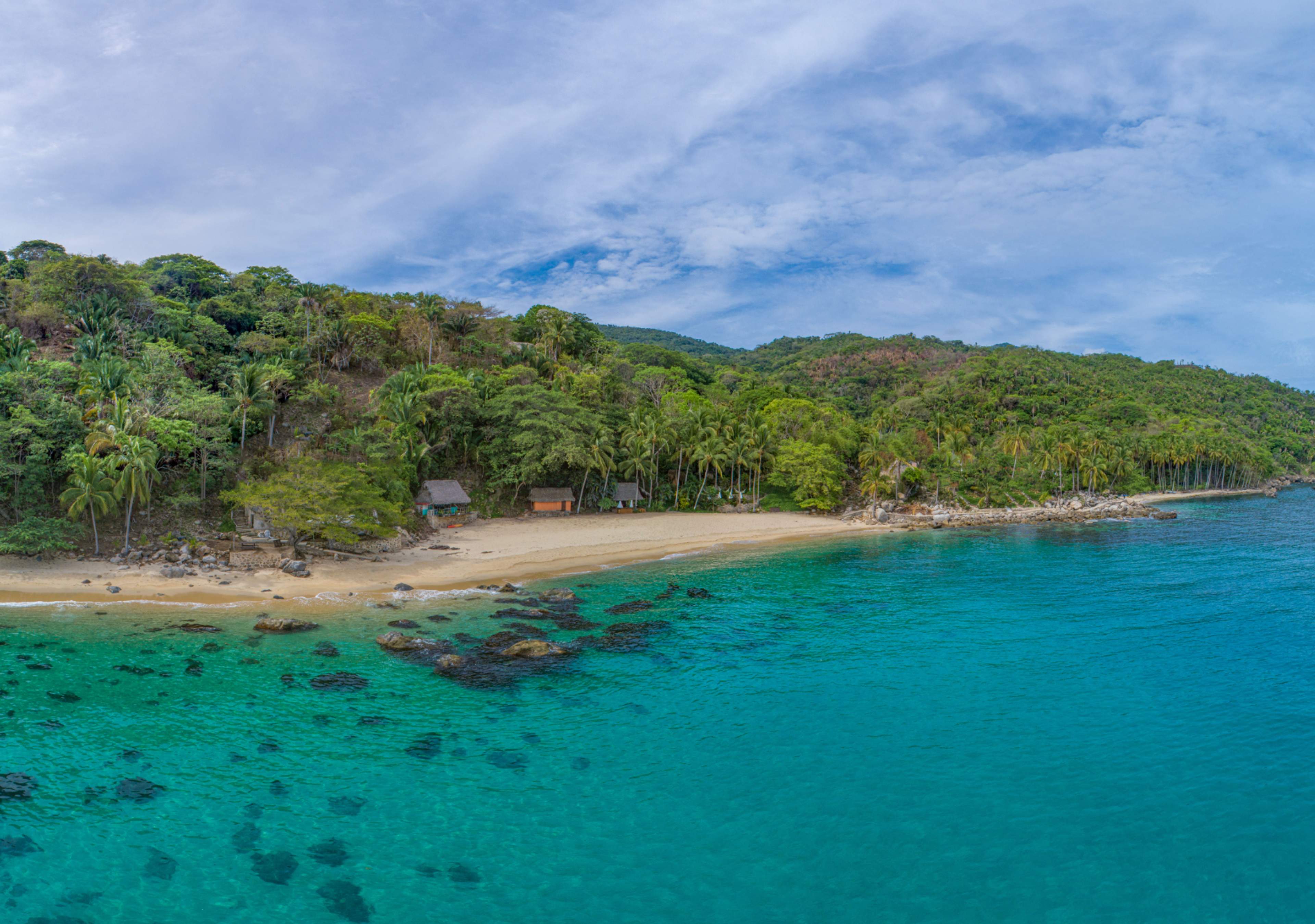 Aerial view of Pizota beach with golden sand, clear turquoise waters, and lush greenery in Puerto Vallarta, Mexico.