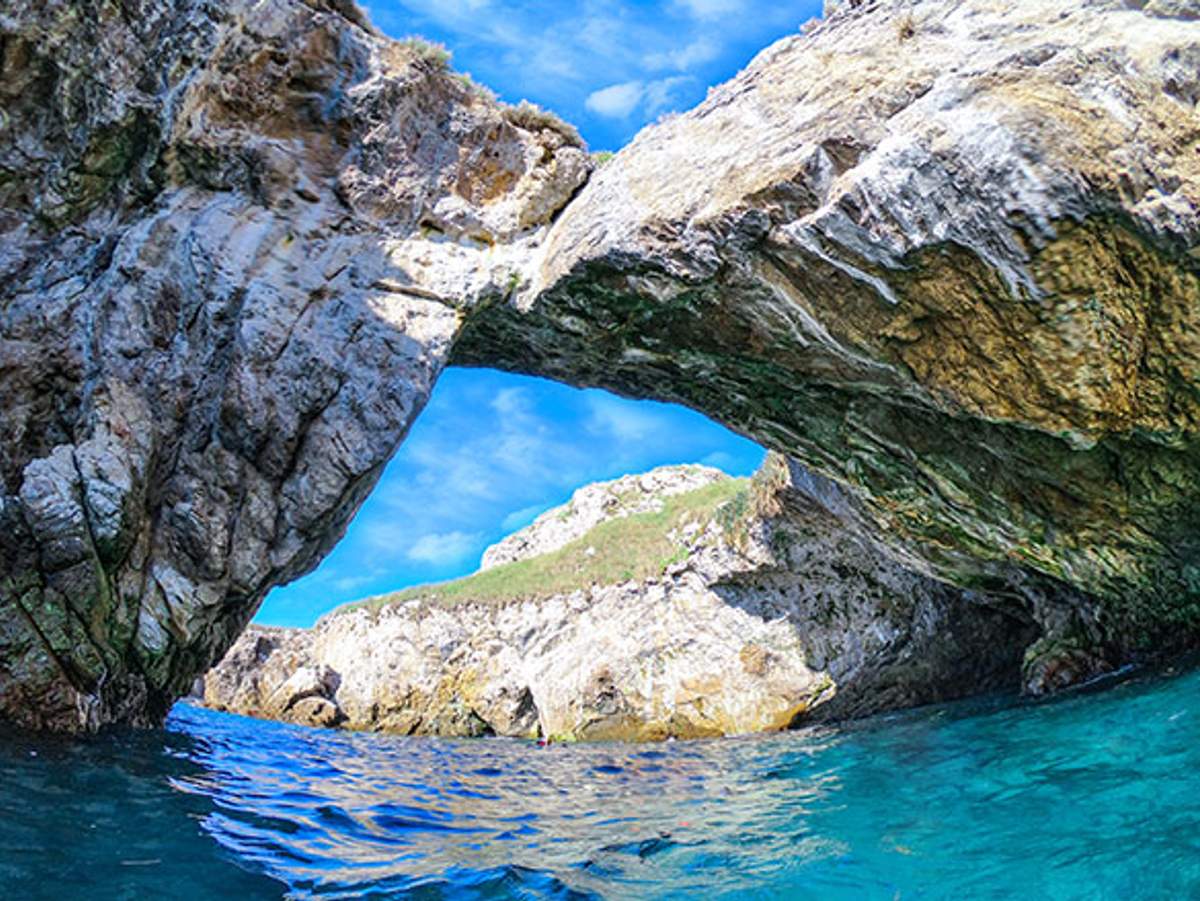 Un arco de roca natural en las Islas Marietas, con agua azul clara debajo y un cielo azul brillante arriba.