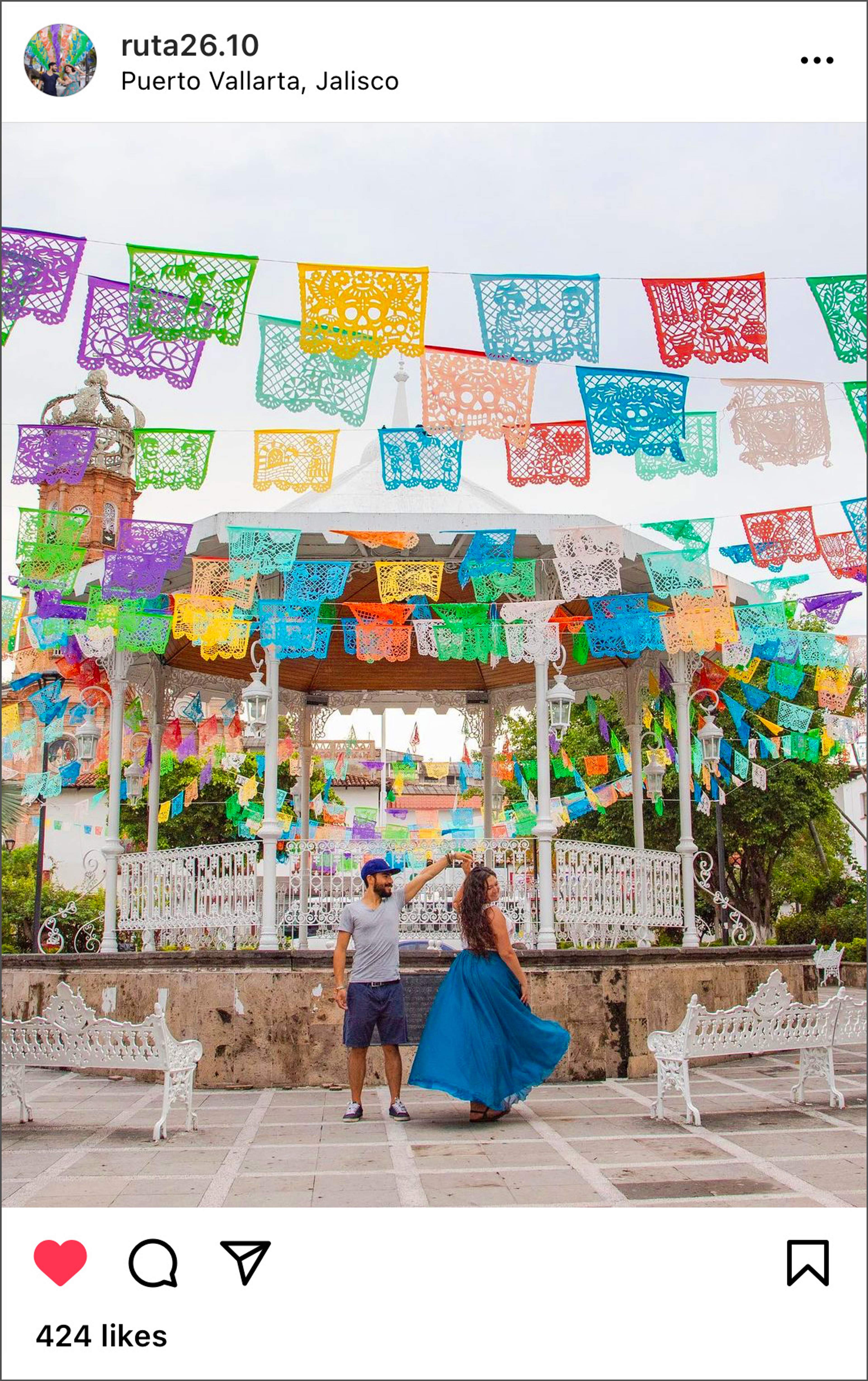 Couple dancing in front of gazebo decorated with colorful flags in Puerto Vallarta, Jalisco.