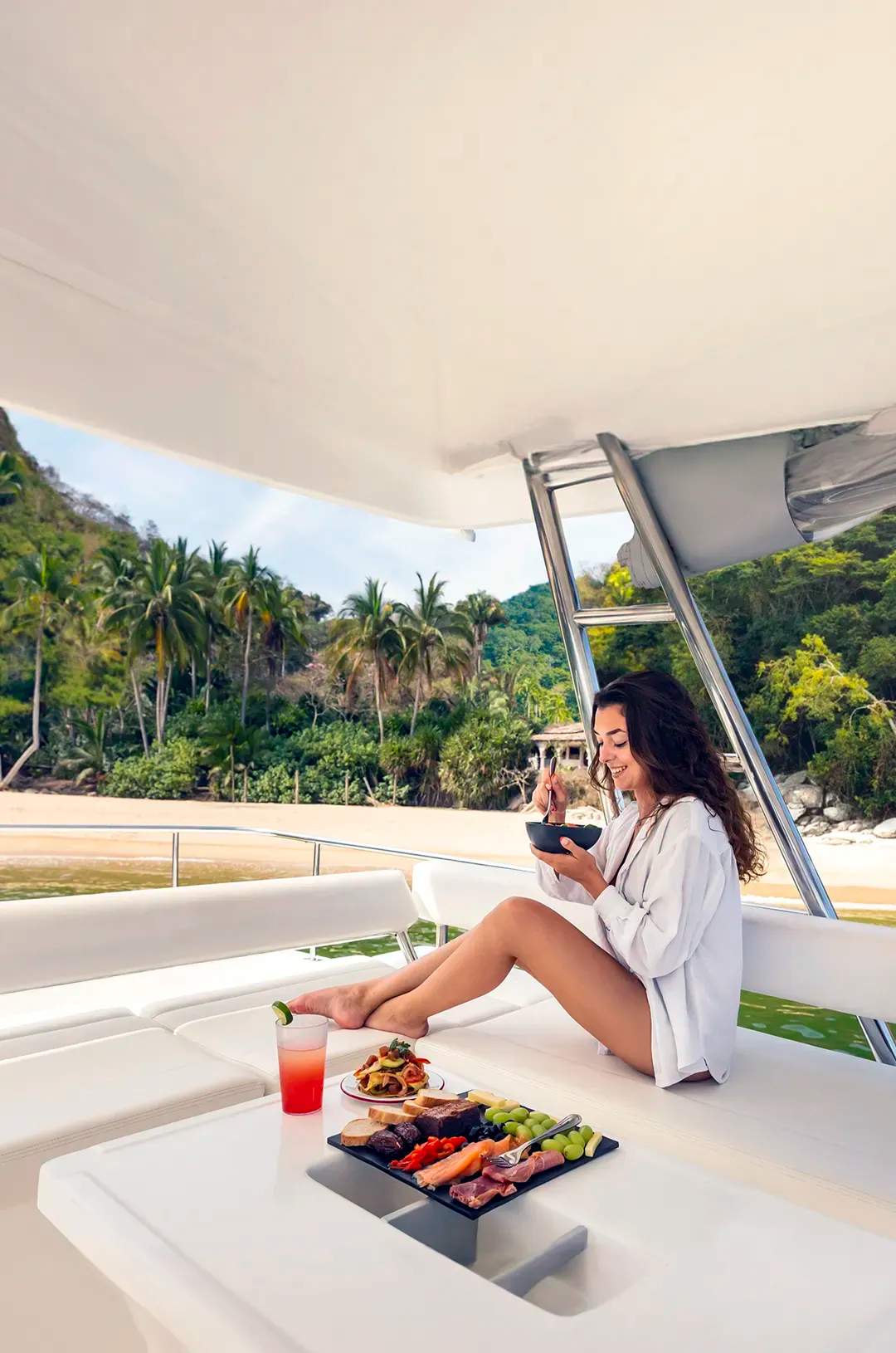Mujer disfrutando de una comida y barra libre en un yate de lujo frente a la playa Majahuitas, Puerto Vallarta.