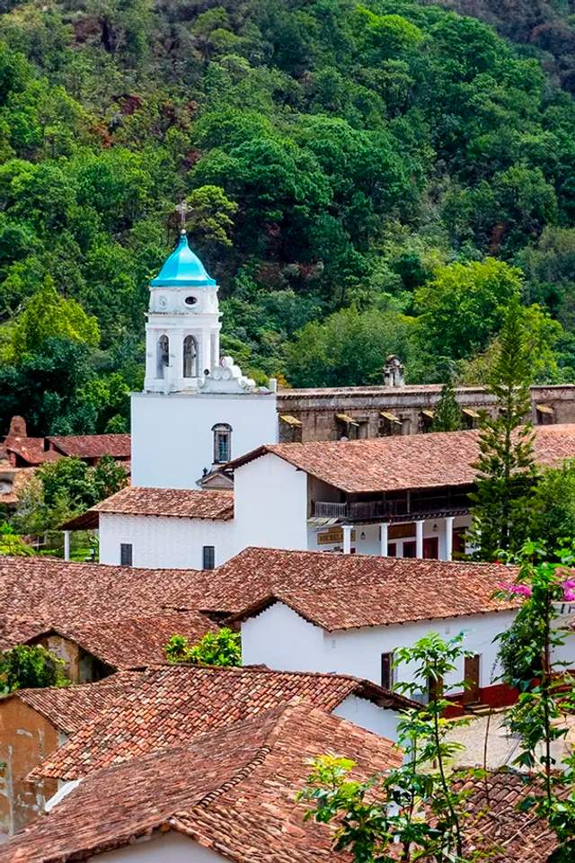 Aerial view of San Sebastian del Oeste, featuring its iconic white church with a blue dome amidst the Sierra Madre mountains.