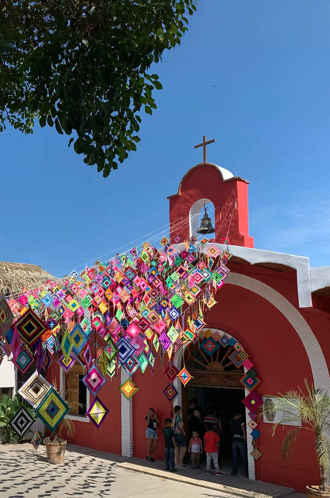 Colorful Ojos de Dios, an amulet of the Wirarika culture, hanging outside Sayulita's church.