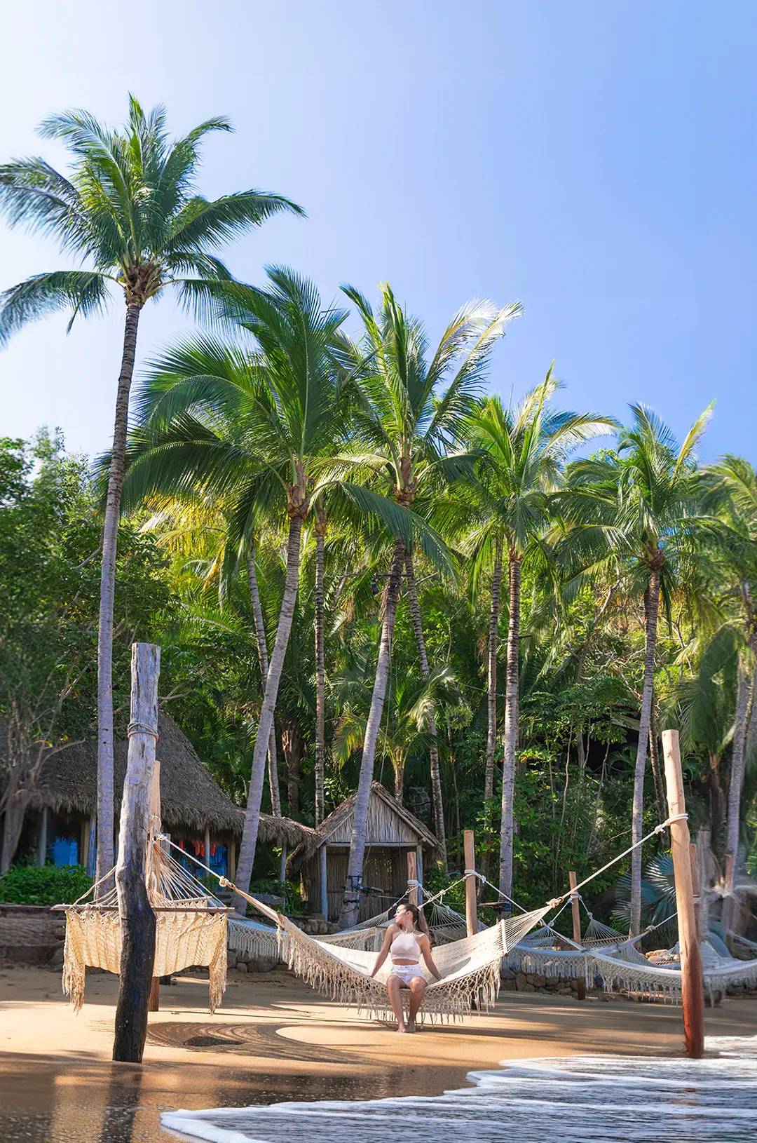 Woman relaxing in a hammock over the waves in the prettiest beach in Puerto Vallarta.