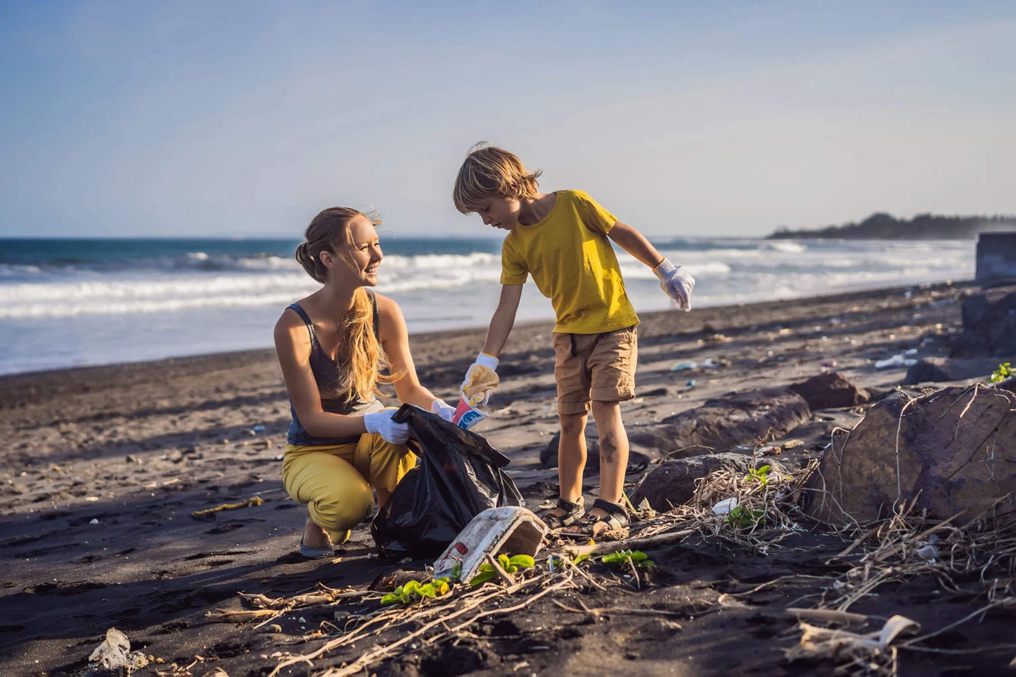Madre e hijo limpian juntos una playa, promoviendo el turismo sostenible y la conciencia ambiental