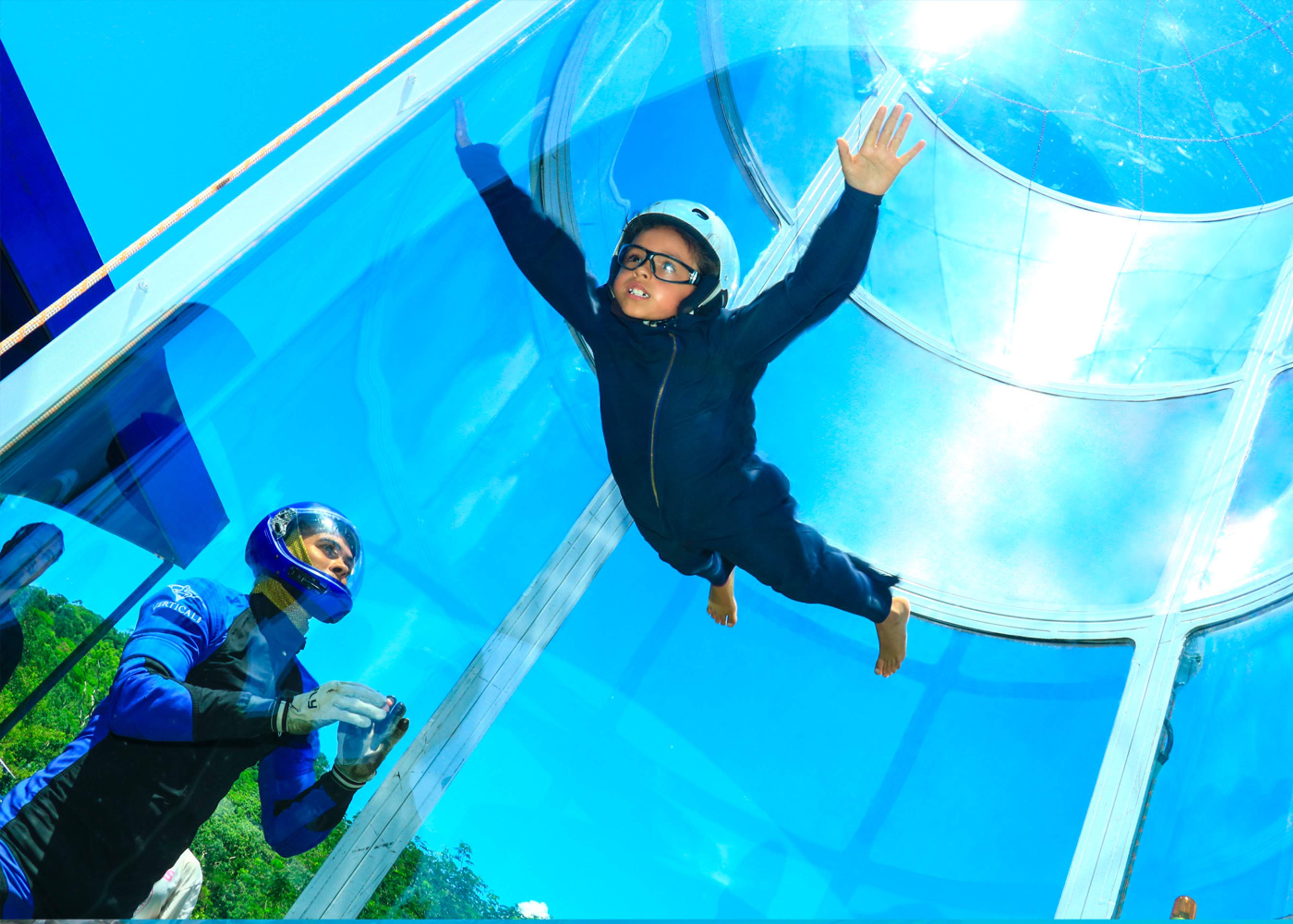 A child experiences skydiving simulation during extreme vacations in Puerto Vallarta, guided by an instructor in a wind tunnel.