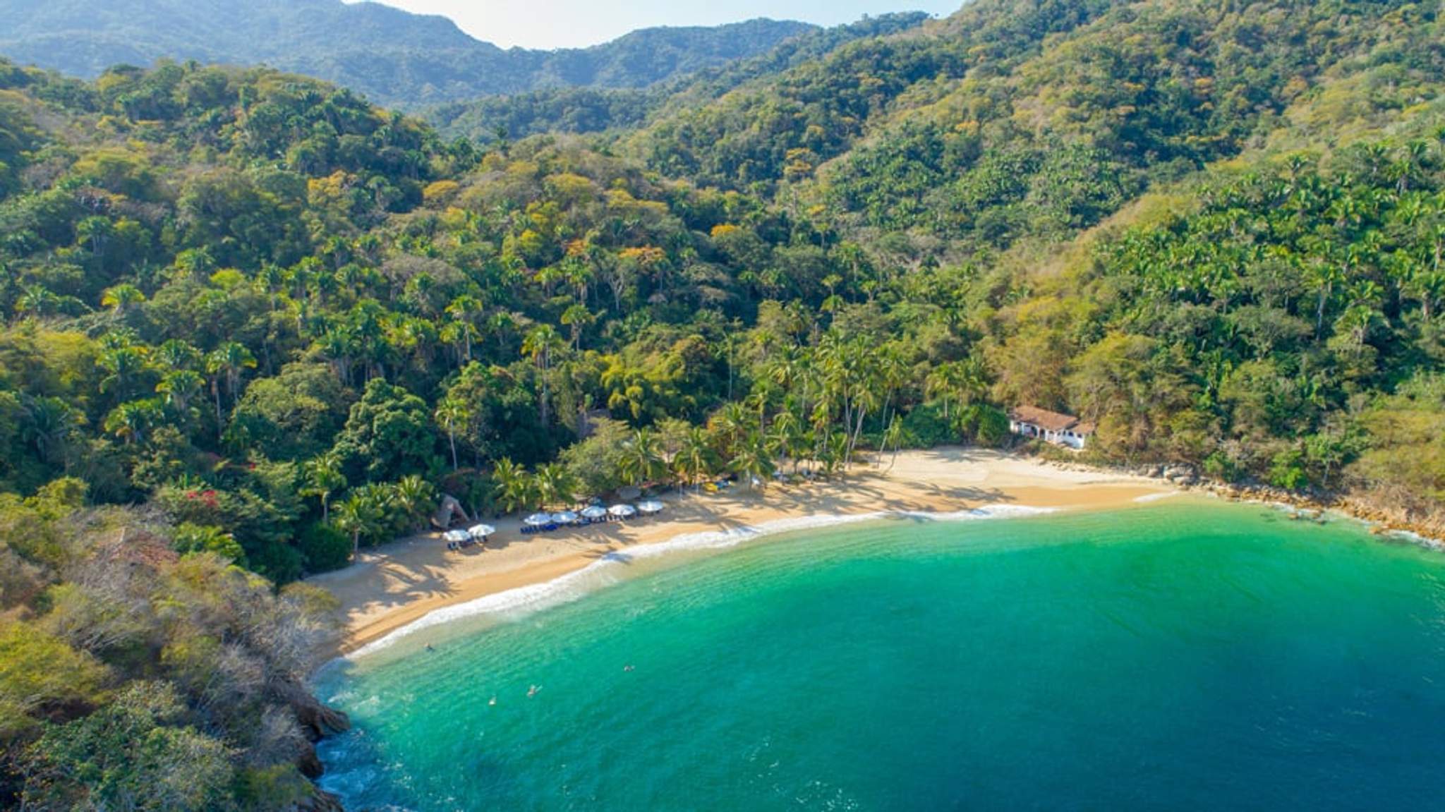 Aerial view of Majahuitas, a secluded beach with golden sand, lush greenery, and turquoise waters in Puerto Vallarta, Mexico.