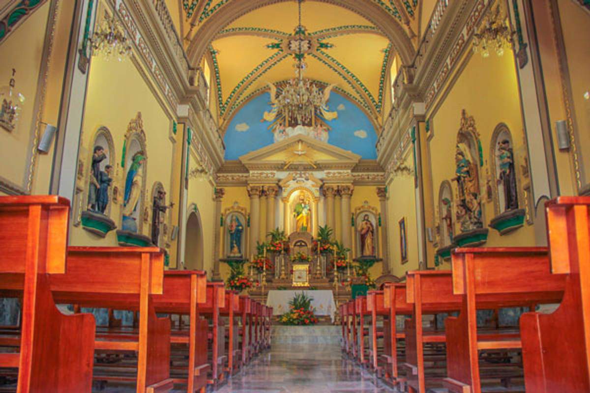 Interior of a church in Mascota, Jalisco, featuring wooden pews, decorated altars, and an adorned vaulted ceiling.