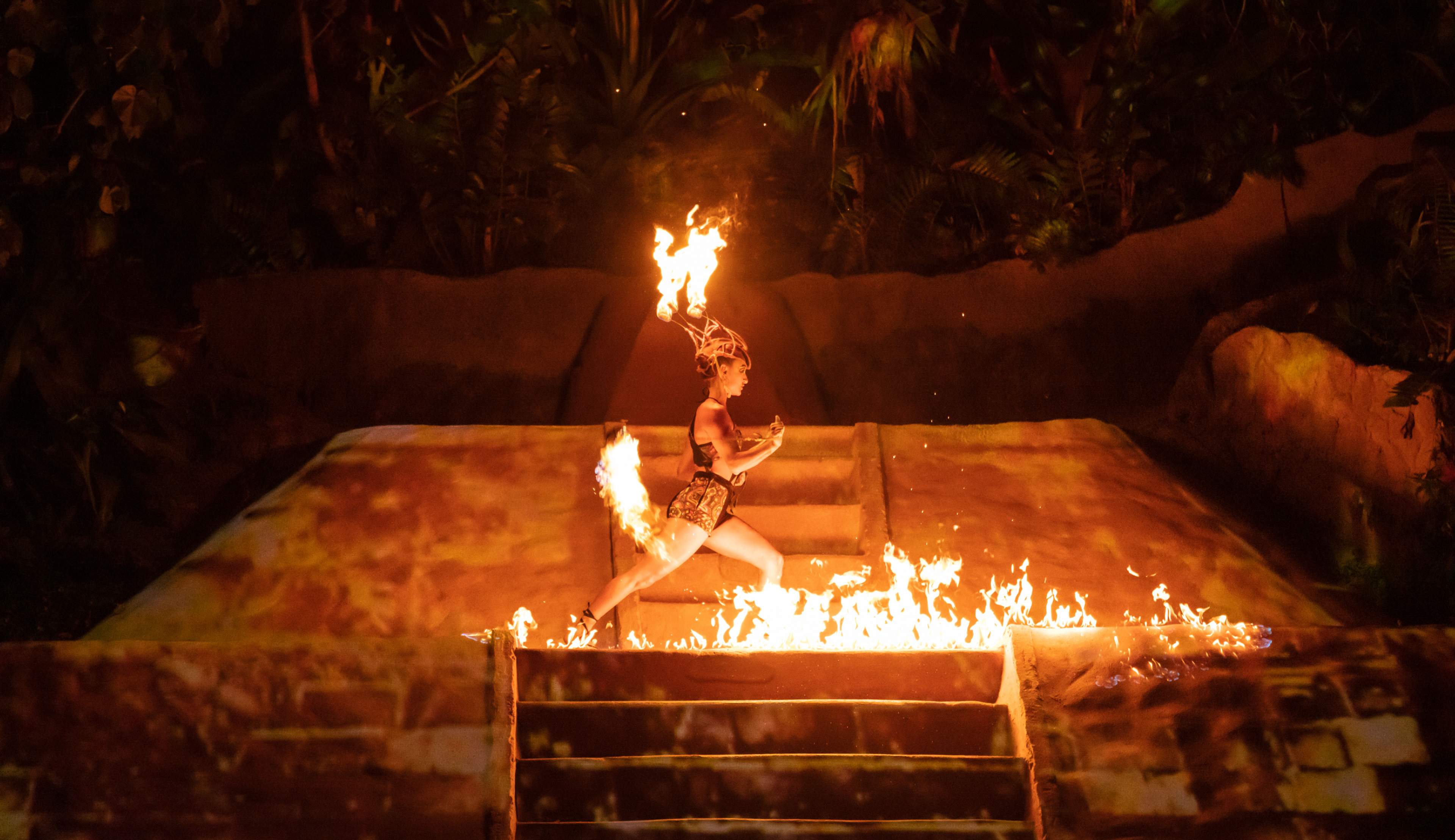 Un artista bailando con fuego en el escenario durante el espectáculo ALMA en Las Caletas, Puerto Vallarta, México.