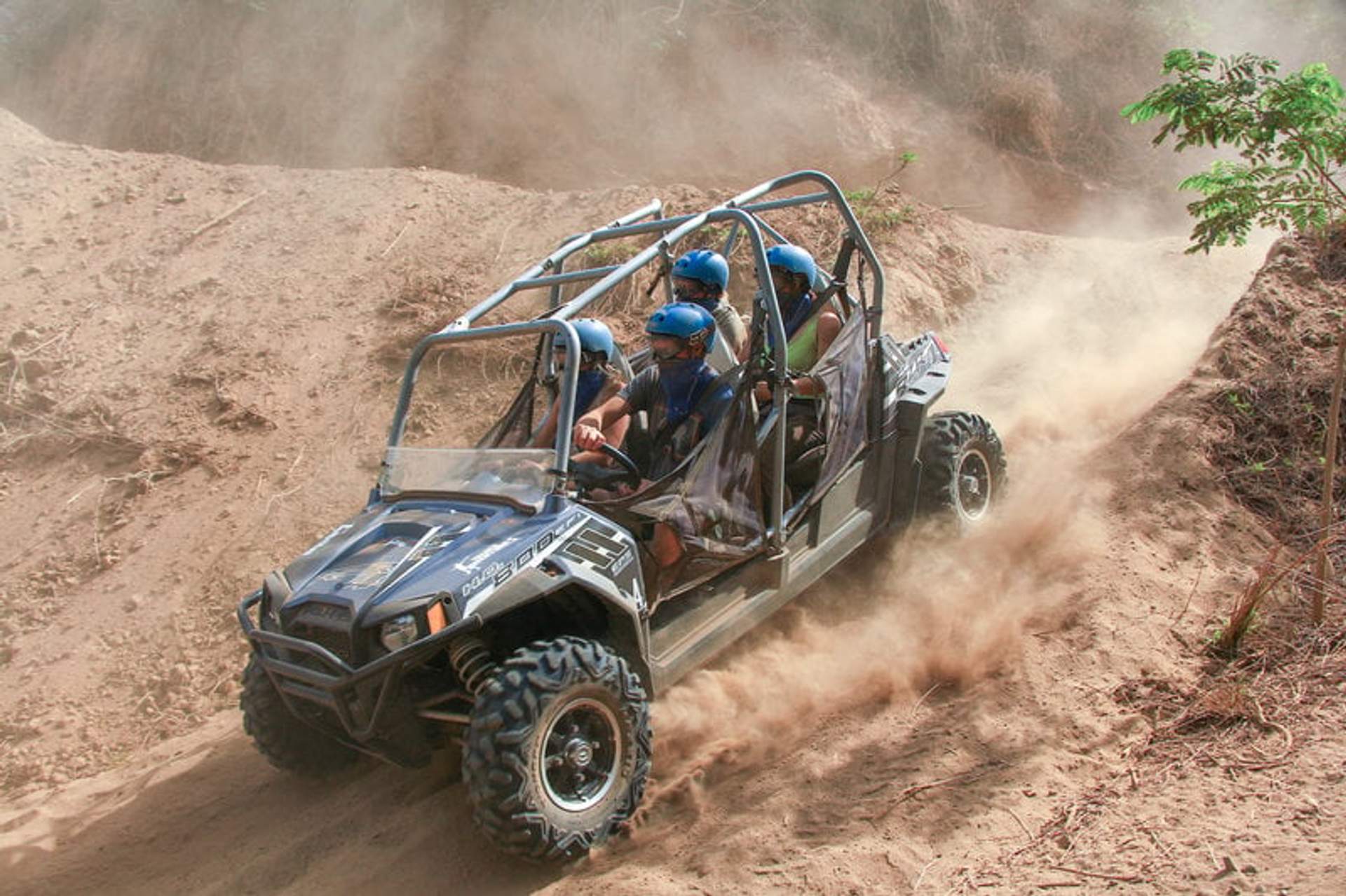Group of people riding a Polaris RZR UTV on a dusty off-road trail in Sayulita, Mexico, wearing helmets and enjoying the adventure.