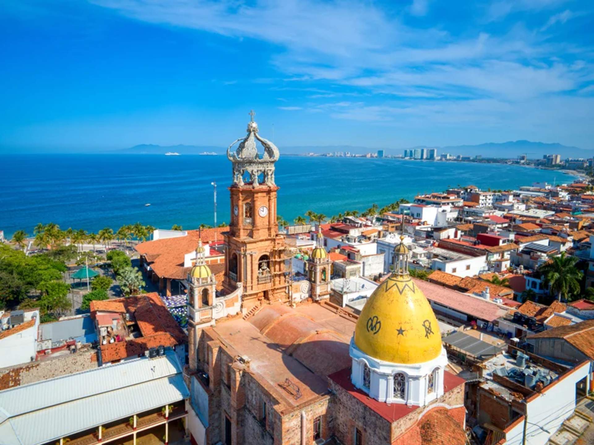 Aerial view of downtown Puerto Vallarta, featuring the iconic Church of Our Lady of Guadalupe with the ocean in the background.