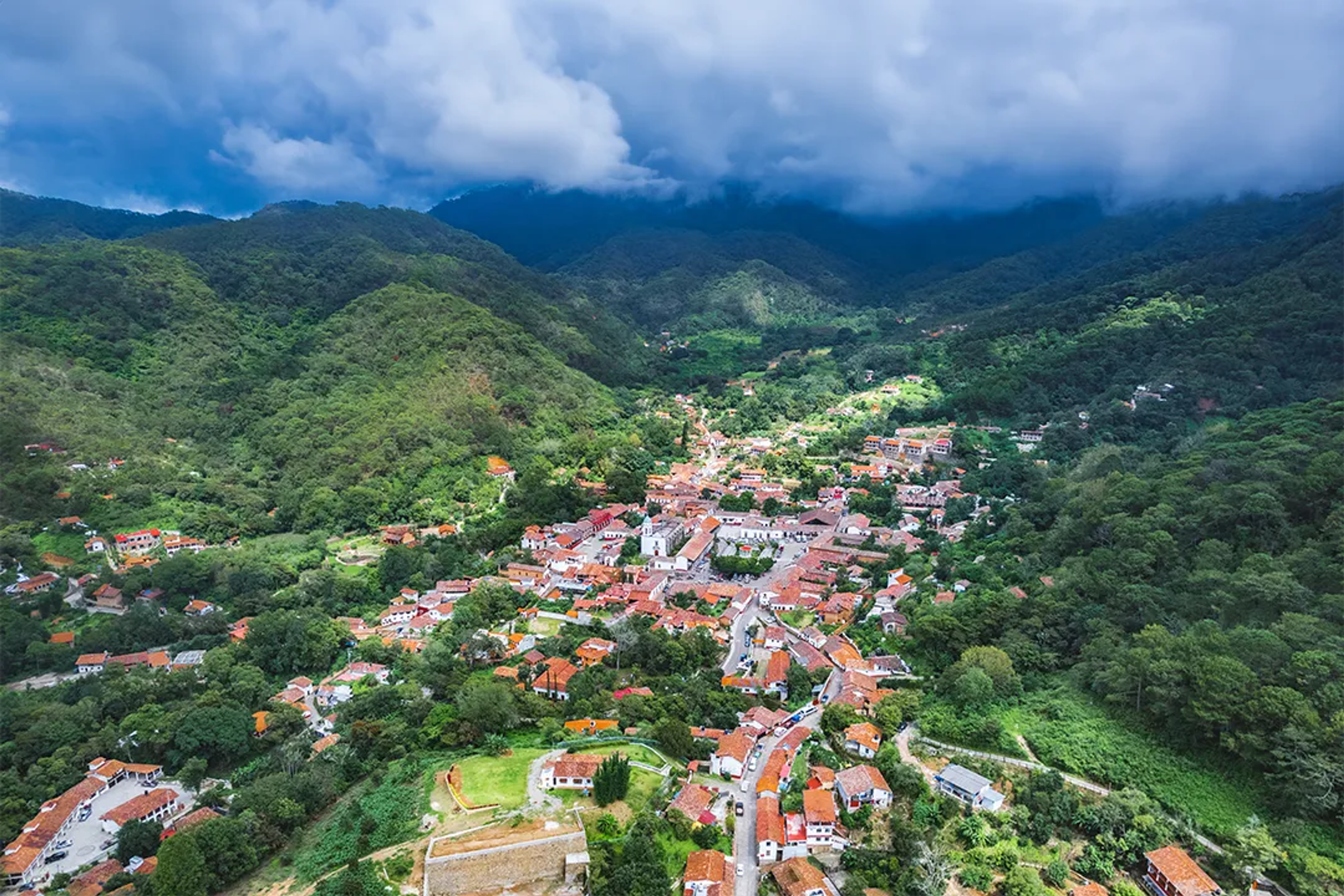 Vista aérea de San Sebastián del Oeste rodeado de montañas verdes, ideal para la aventura.