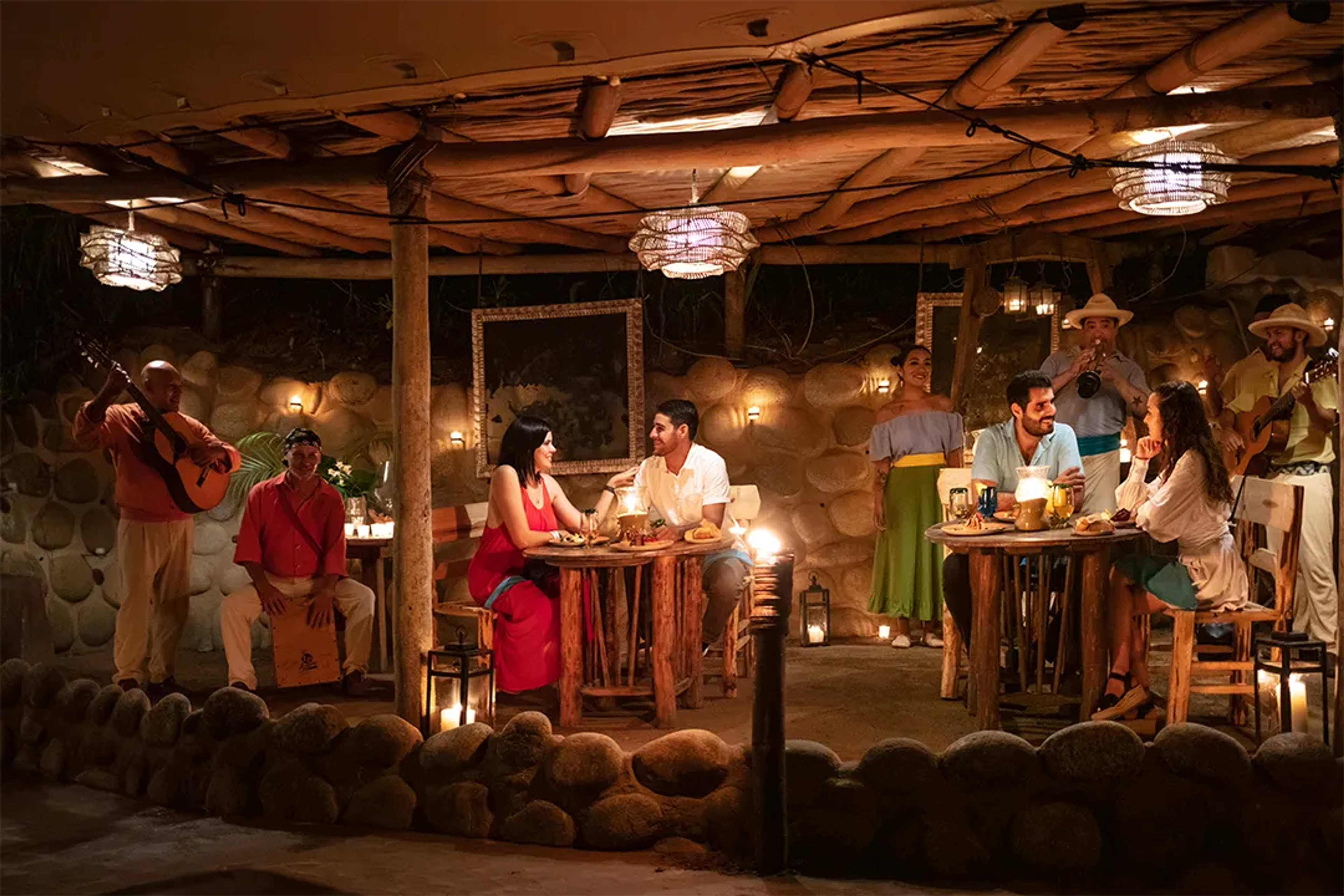 Couples enjoying a candlelit dinner with live music in a rustic restaurant.