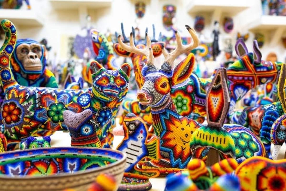 Arte Huichol vibrante, con esculturas de animales y tazones coloridos, mostrando la artesanía tradicional mexicana.
